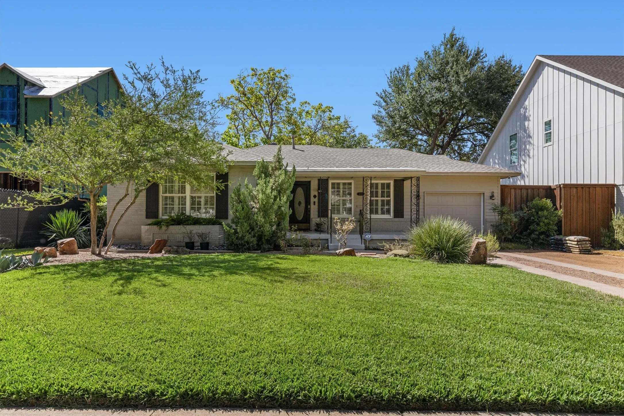 Well-maintained front lawn, mature trees, single-story residence, attached garage, and stone landscaping accents