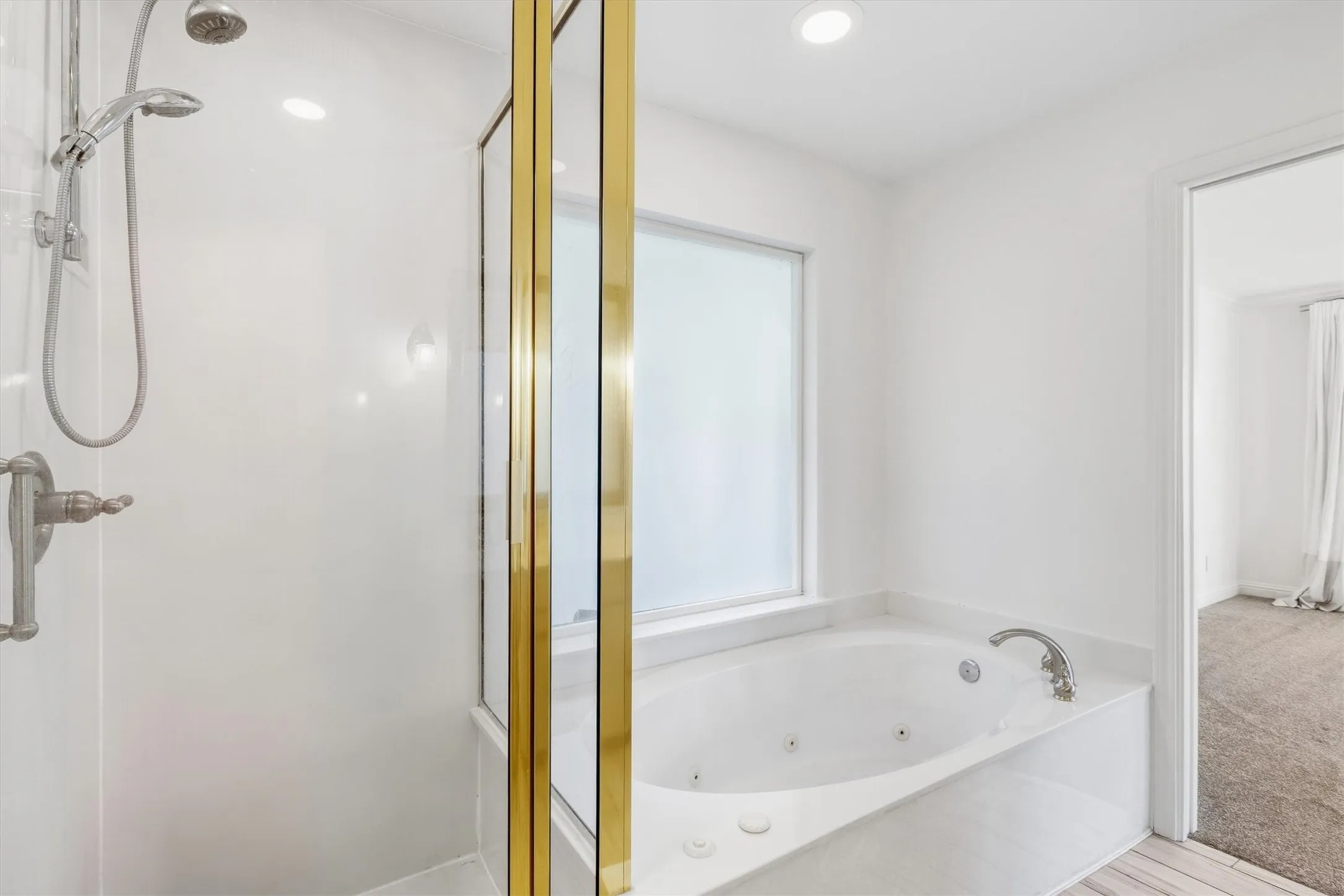 Walk-in shower with a gold-finish frame, built-in jetted tub, and recessed lighting