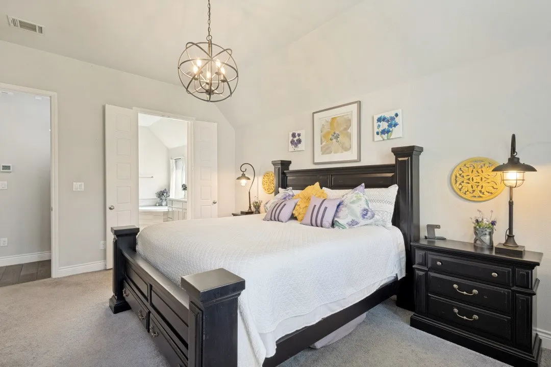 Vaulted ceiling with an orb chandelier, light gray walls, plush carpet flooring, and double doors to an adjoining space