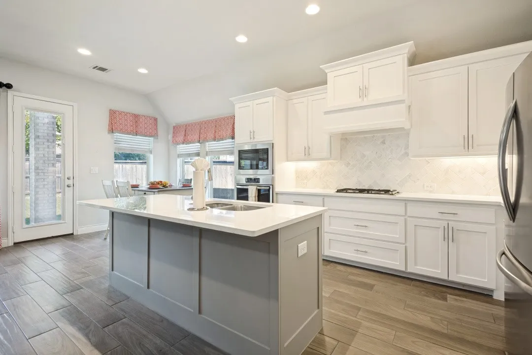 Kitchen featuring a central island with countertop, wood-finish flooring, recessed lighting, white cabinetry, and herringbone tile backsplash