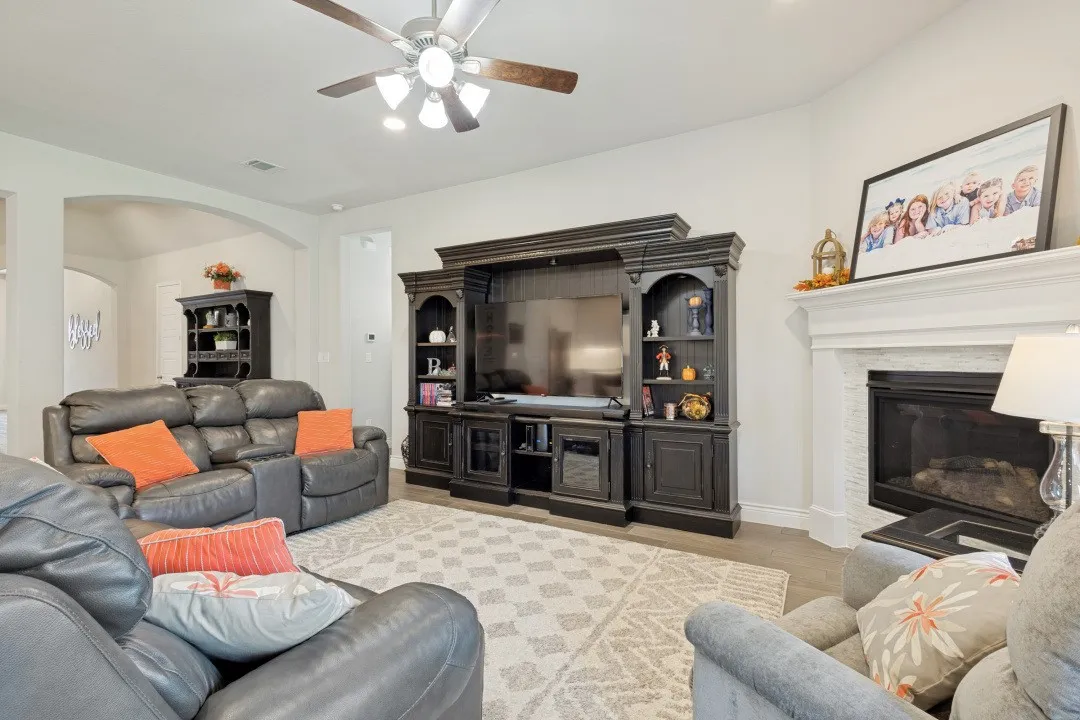Recessed lighting, ceiling fan, wood-finish flooring, fireplace with white mantel, built-in entertainment center