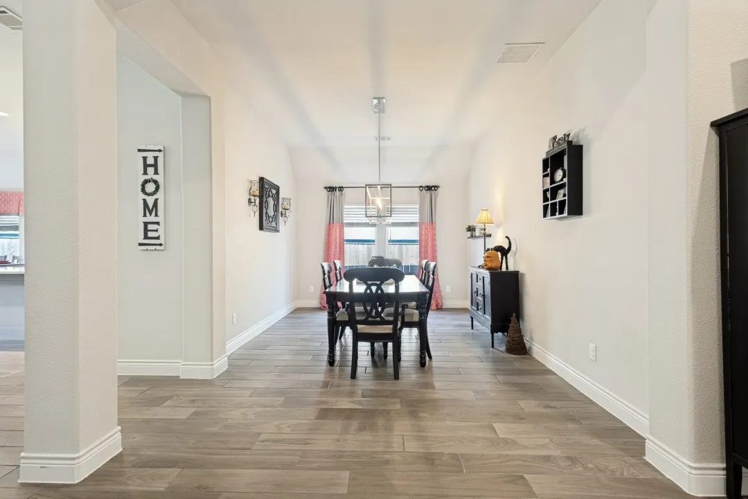 Wood-finish flooring throughout, bright white walls, and a modern ceiling-mounted light fixture