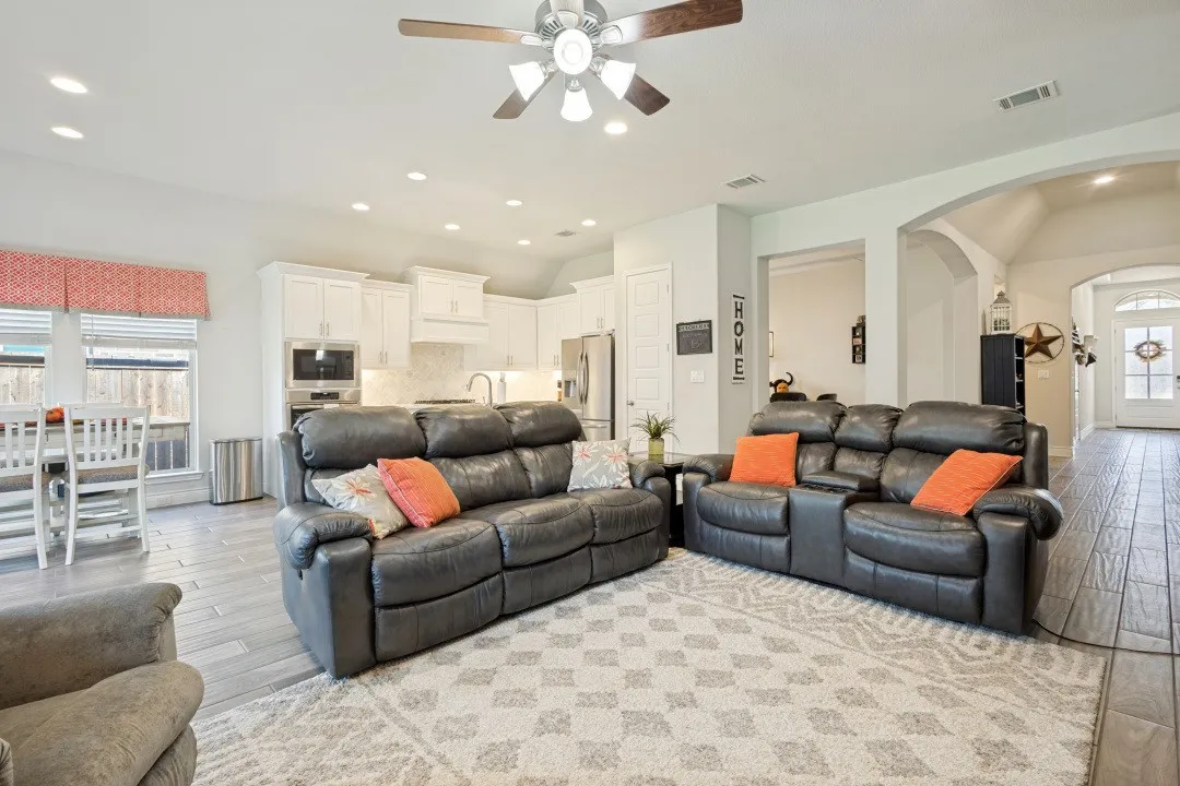 Recessed lighting, wood-finish flooring, white cabinetry, arched doorways, and a ceiling fan