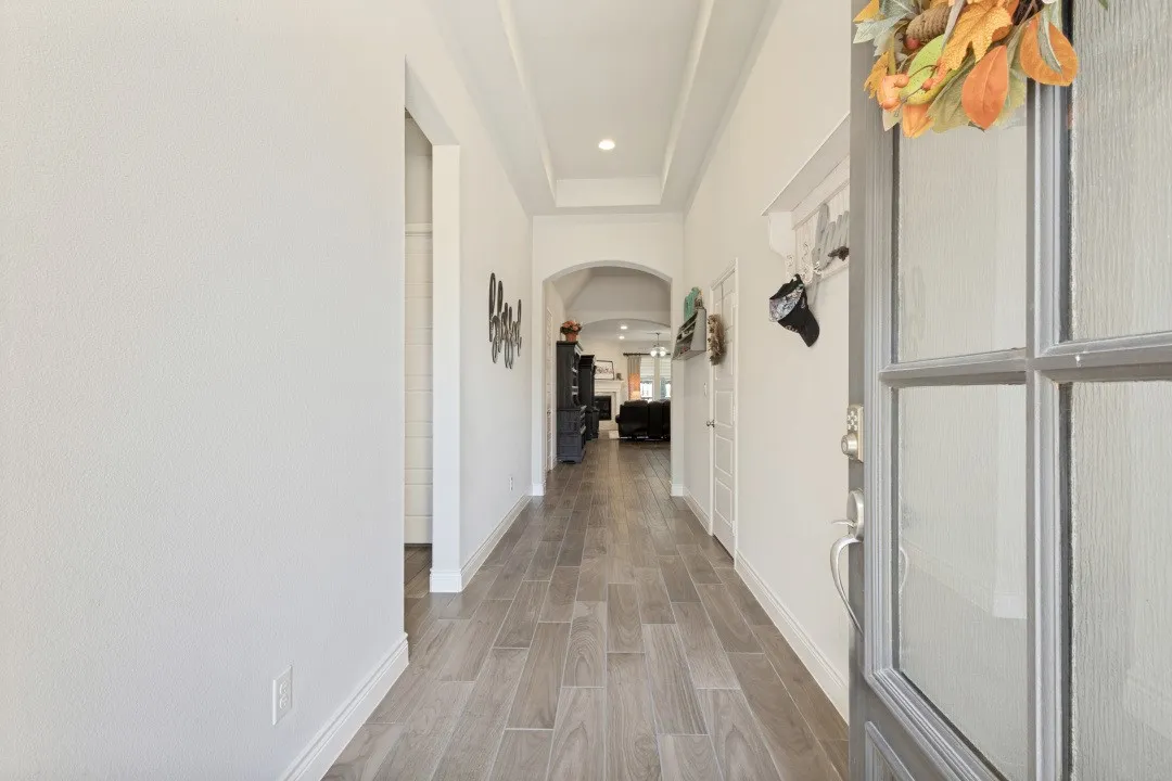 Entryway featuring wood-finish flooring, a tray ceiling with recessed lighting, and an arched doorway