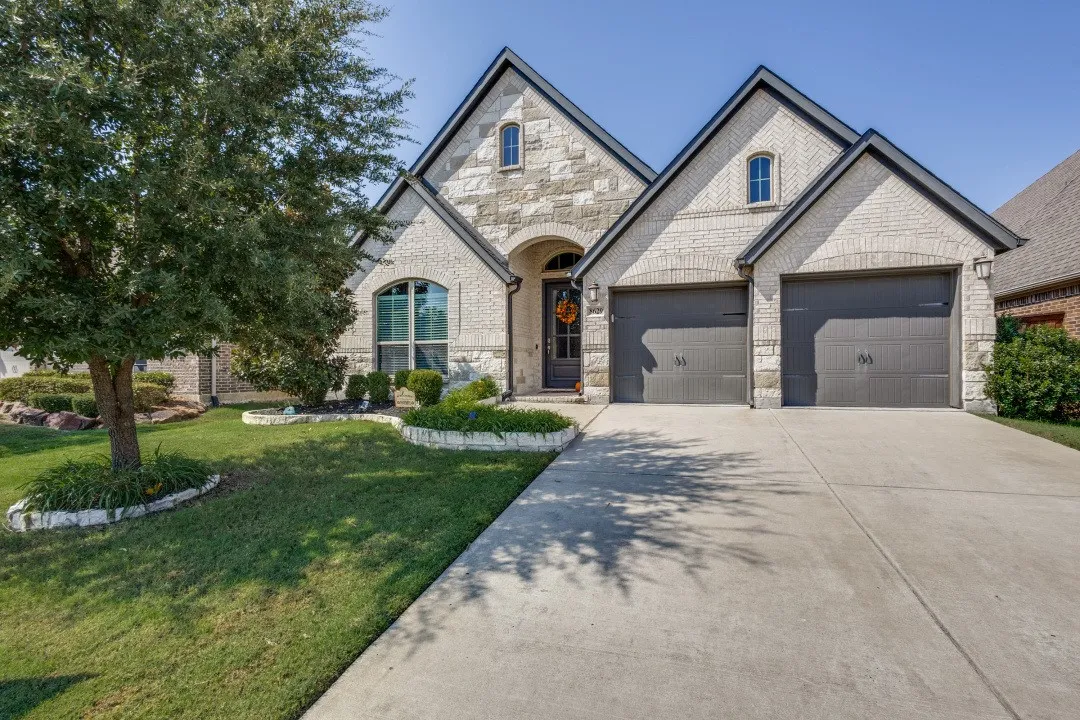 Stone and brick exterior with contrasting dark trim, arched entry, two-car garage, and a concrete​​‌​​​​‌​​‌‌​‌‌​​​‌‌​‌​‌​‌​​​‌​​ driveway