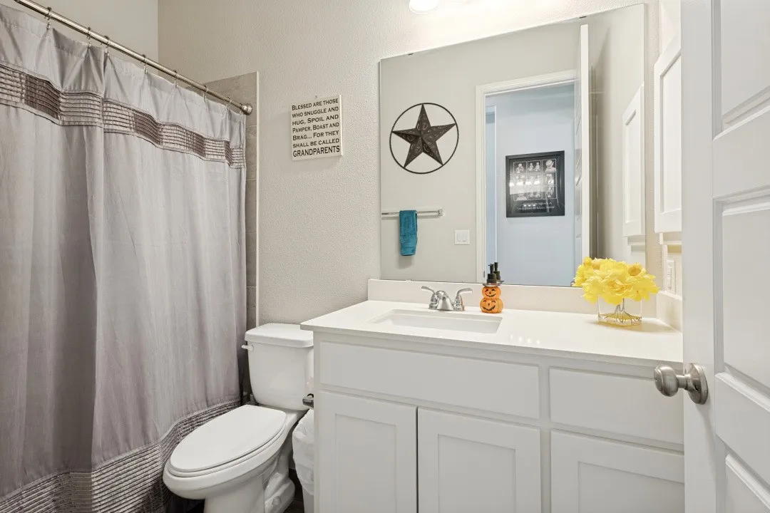 White vanity with built-in sink, brushed nickel faucet, and frameless mirror