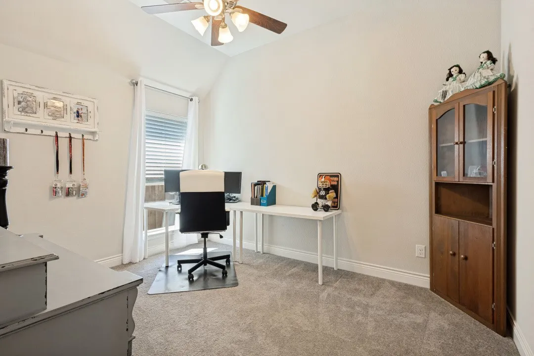 Vaulted ceiling with a ceiling fan, window with blinds and curtains, neutral wall paint, and gray carpet flooring