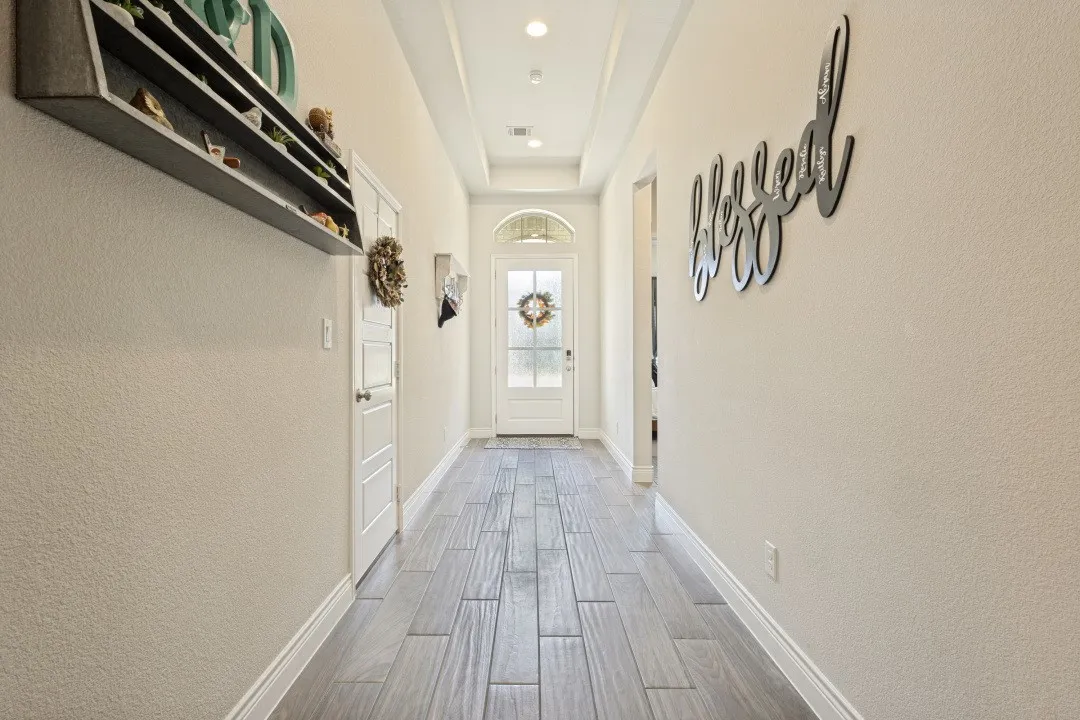 Arched entry door with transom window, wood-finish flooring, recessed lighting, and tray ceiling