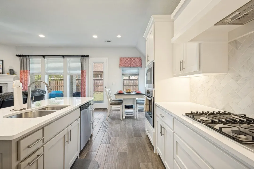 Kitchen featuring white cabinetry, stainless steel appliances, wood-finish flooring, and a gas cooktop