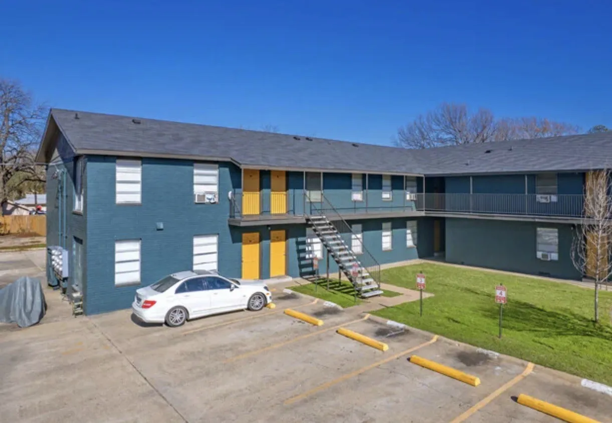 Exterior apartment building with a dark blue facade, multiple windows, and bright yellow entry doors