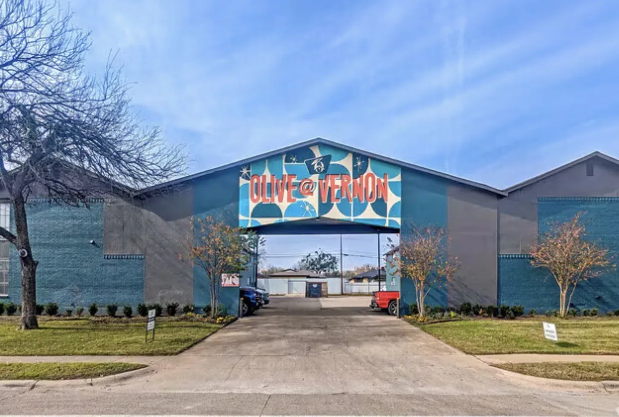 Building exterior with a prominent arched entryway, a pitched roofline, and a decorative facade featuring graphic art