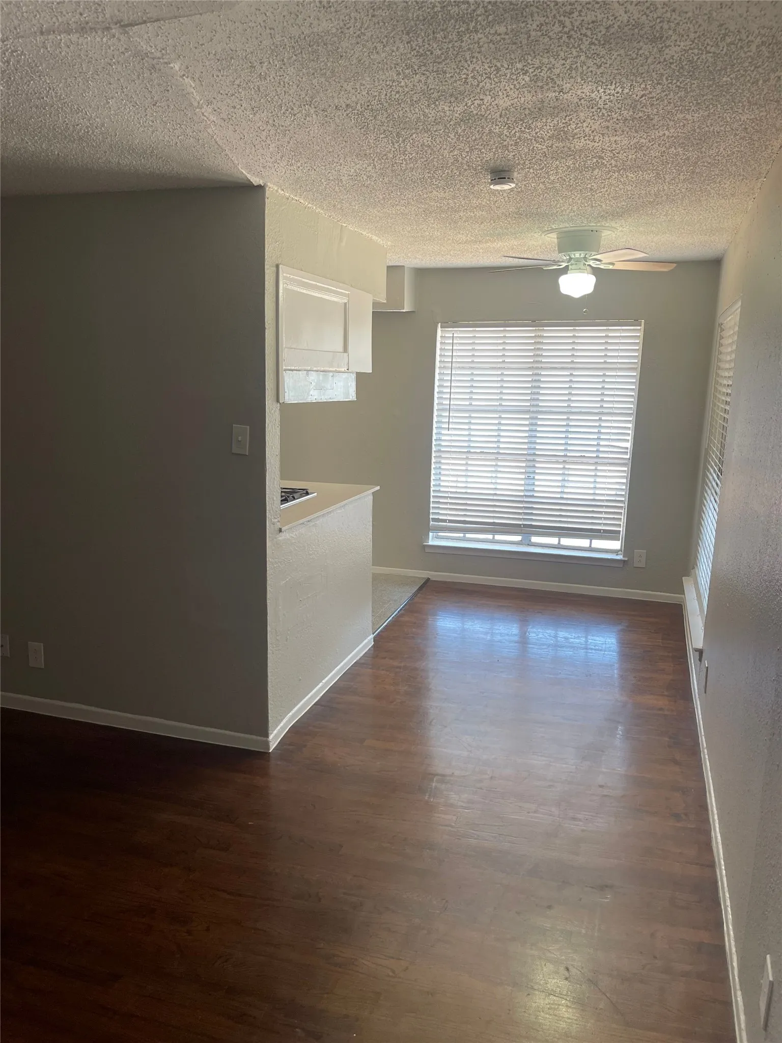 Wood-finish flooring with a ceiling fan and window with blinds