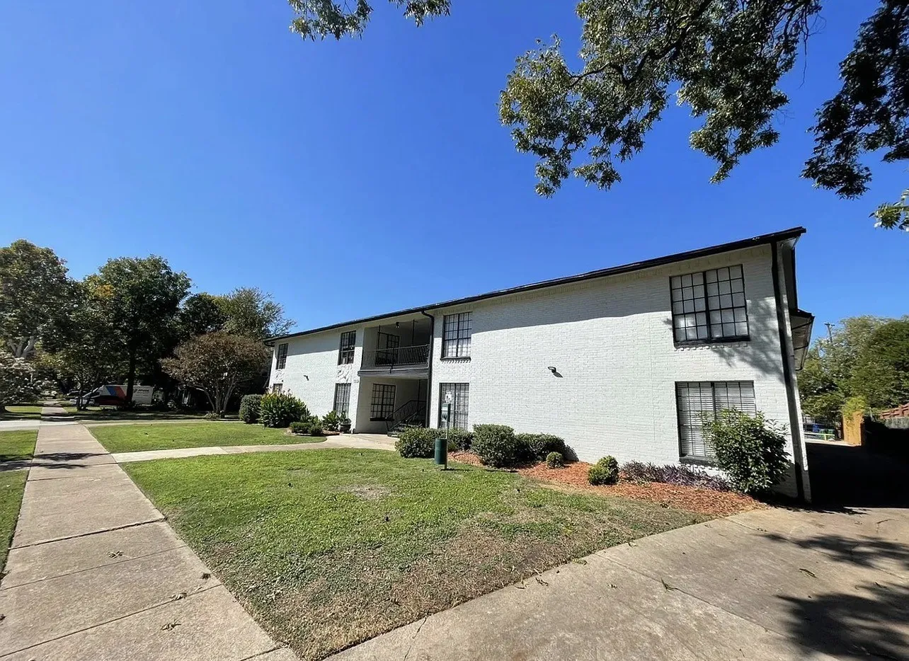 Two-story exterior with white painted brick, black-framed windows, and a second-story balcony