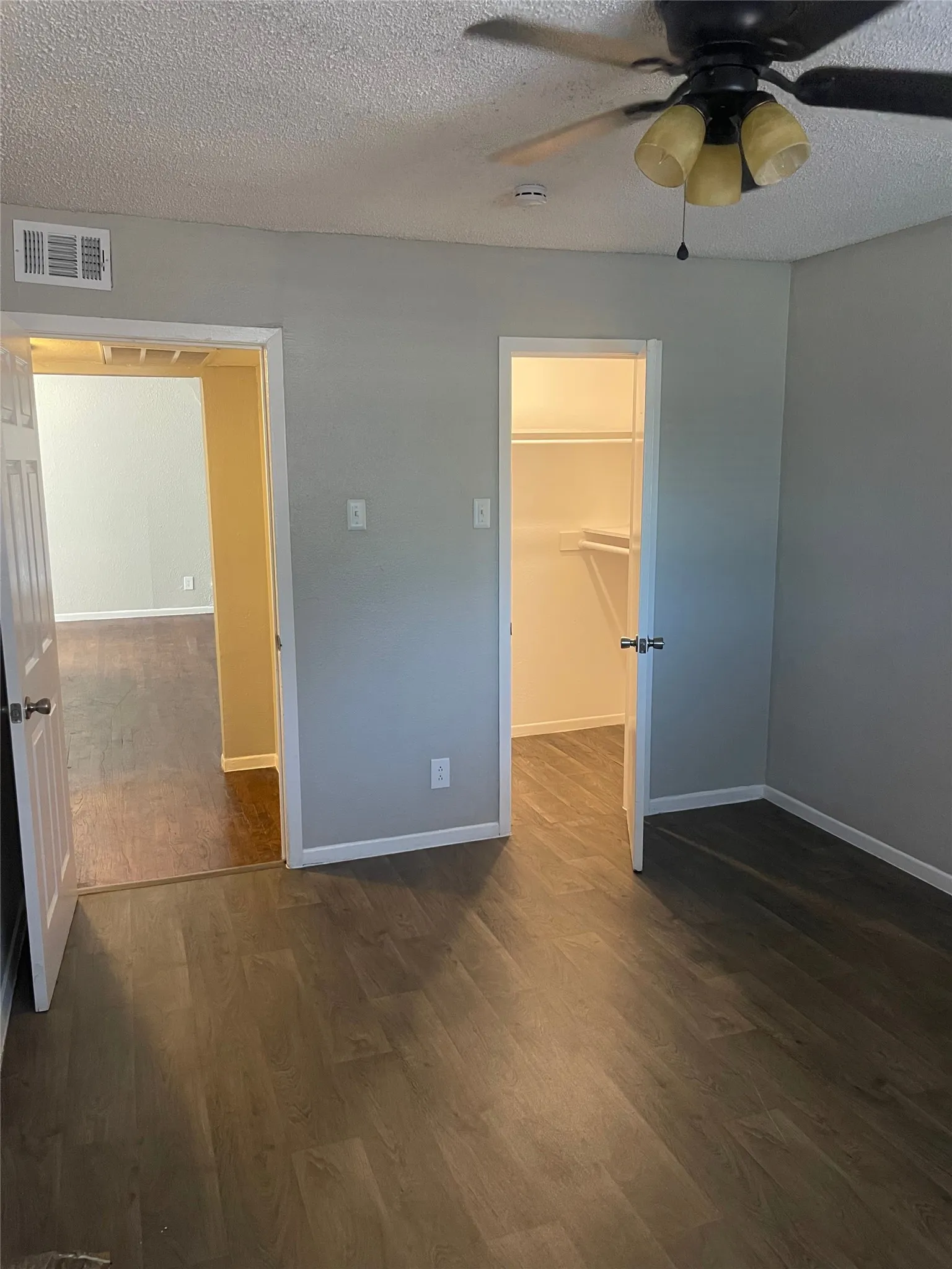 Wood-finish flooring throughout, ceiling fan with integrated lighting, and a built-in closet with shelving
