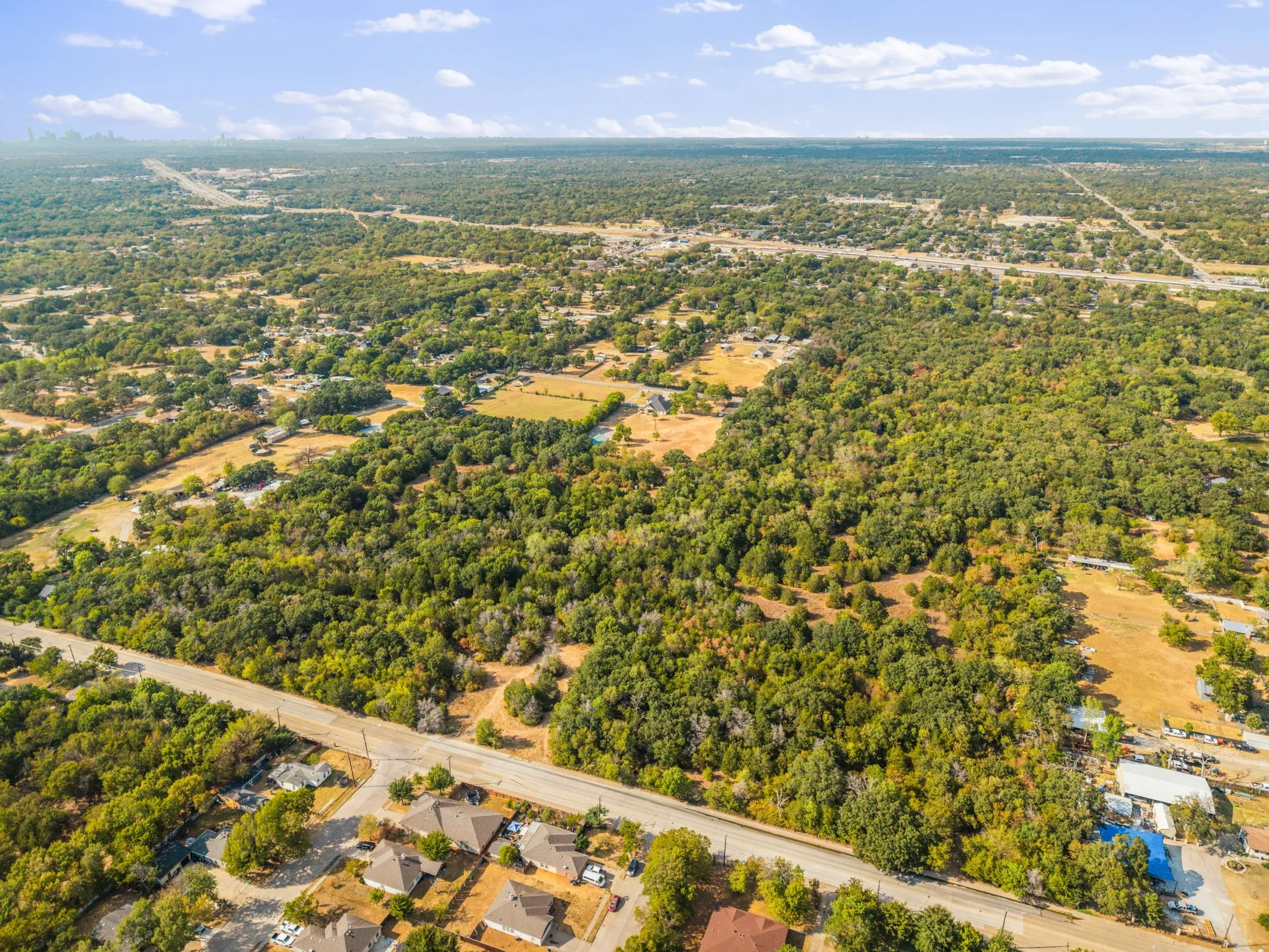 Expansive land parcel featuring dense tree coverage and open clearings, bordered by paved roads