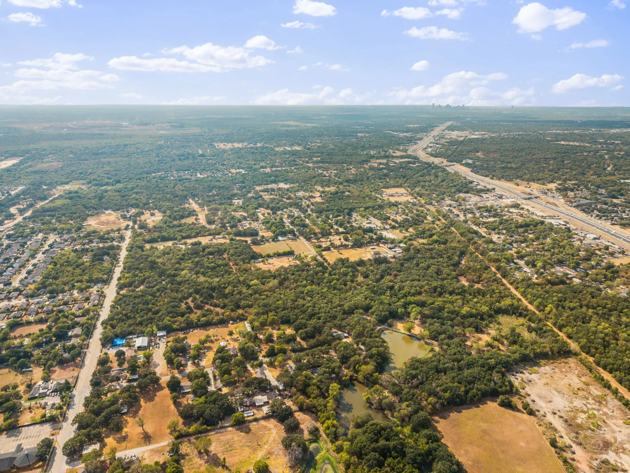Expansive aerial view showcasing a large body of water, extensive tree coverage, and an established residential area