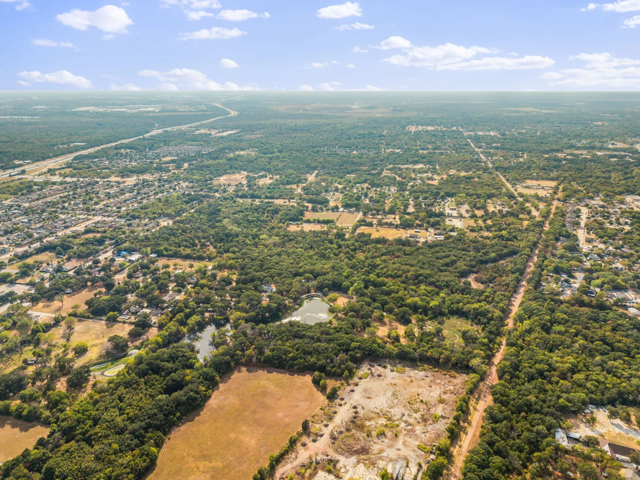 Expansive wooded terrain with visible water features and distant infrastructure