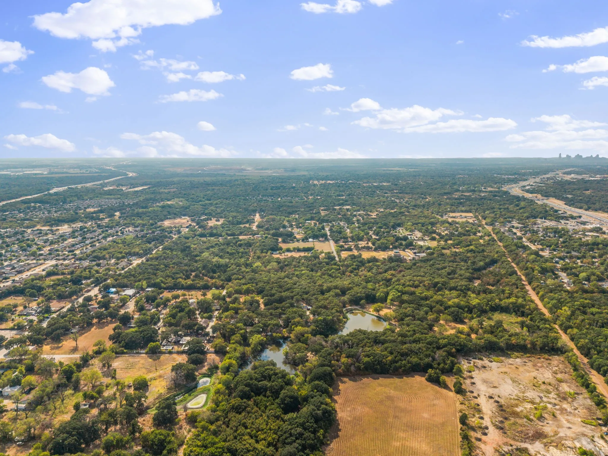 Expansive treed landscape with a visible body of water, offering broad natural surroundings and distant urban features