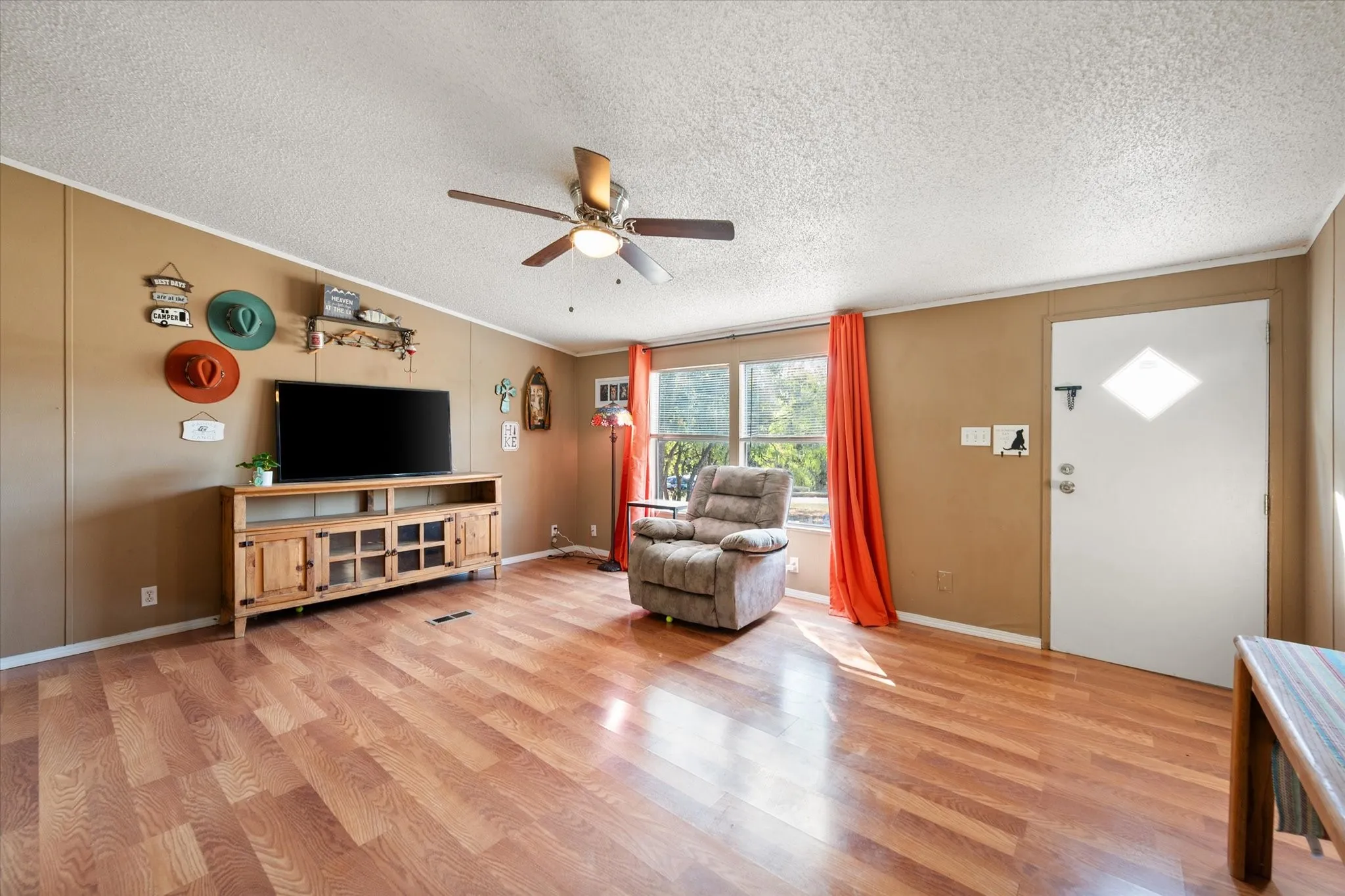 Wood-finish flooring throughout, ceiling fan with integrated lighting, and multiple windows providing natural illumination