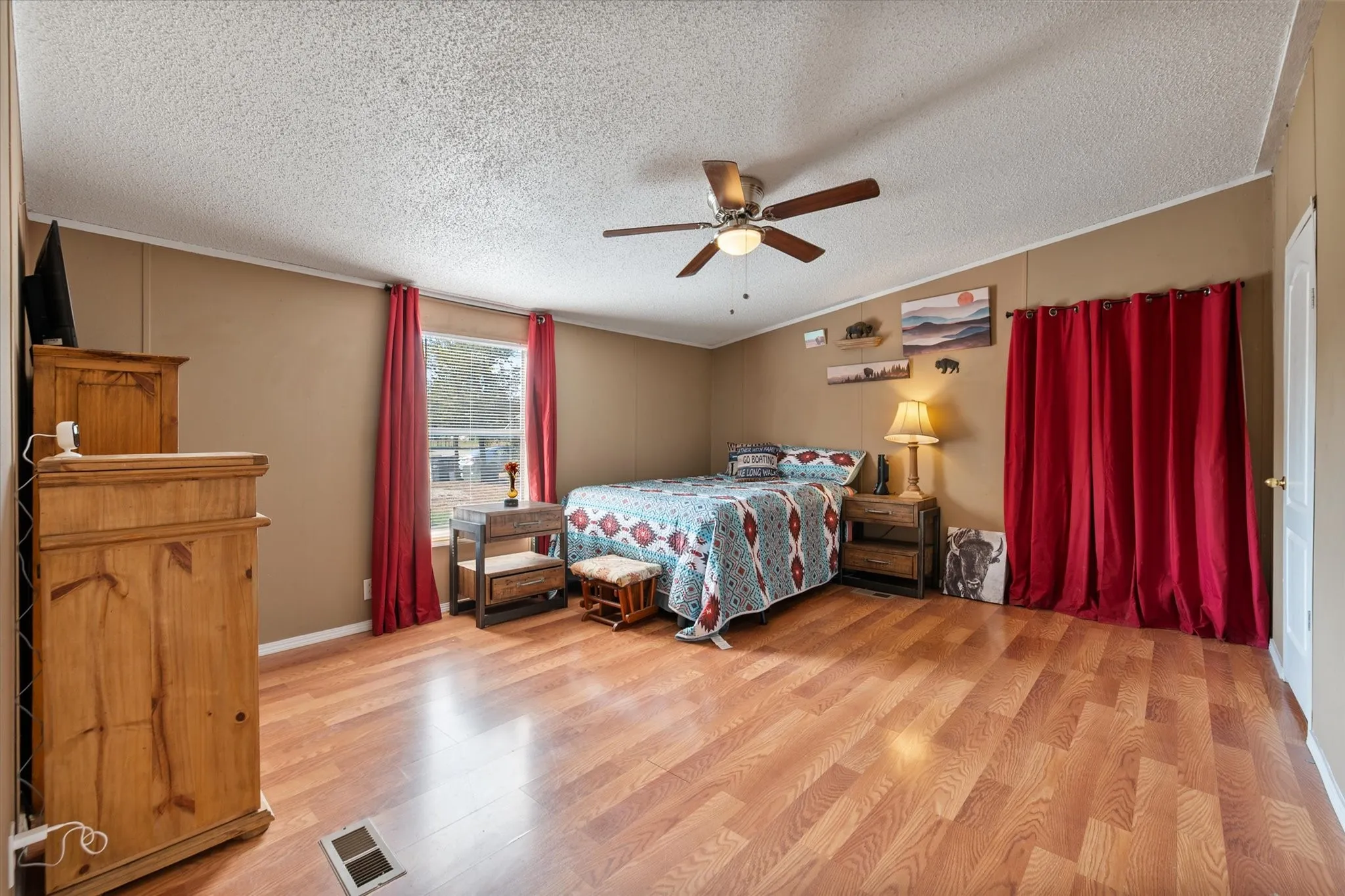 Expansive room featuring wood-finish flooring, a ceiling fan with integrated lighting, and a window with natural light