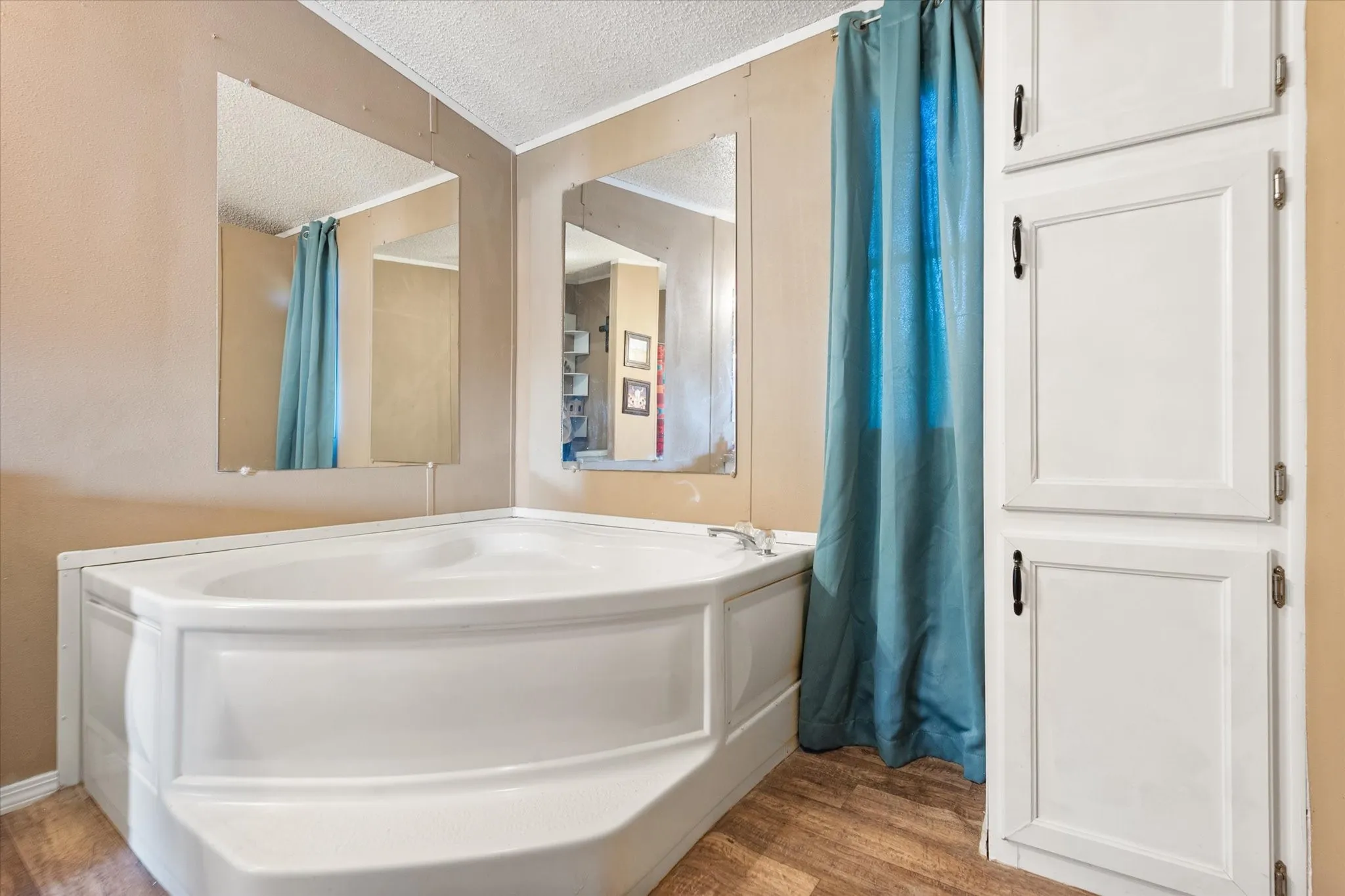 Corner soaking tub with wood-finish flooring and integrated cabinetry