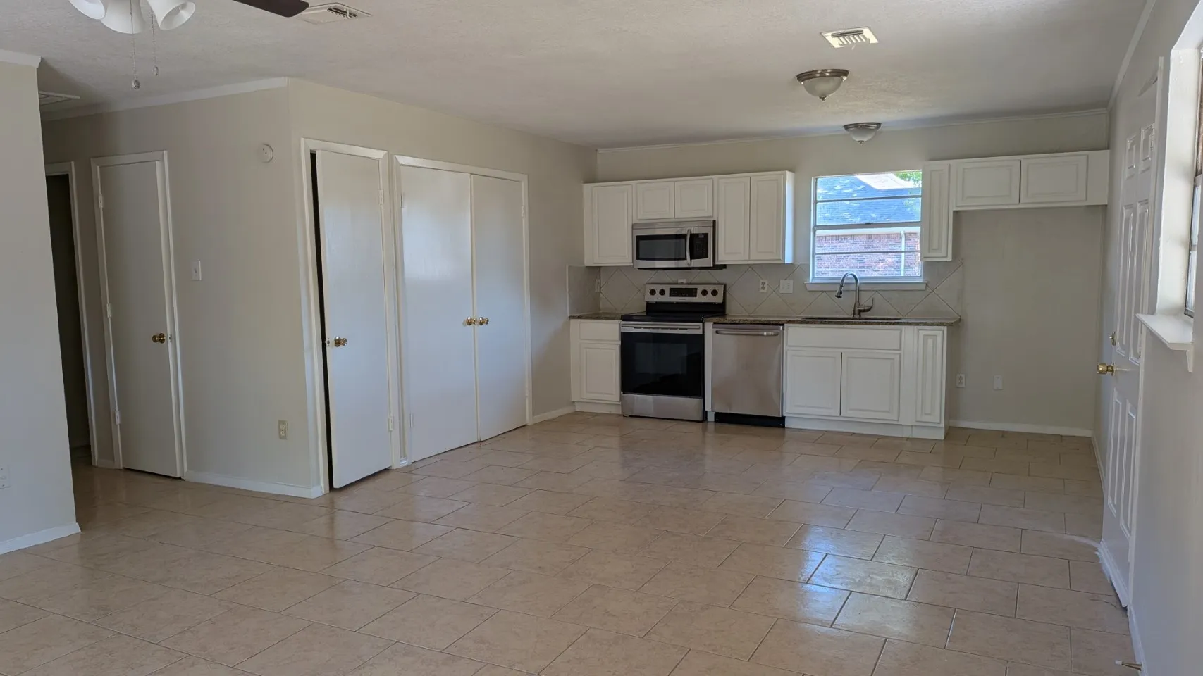 Kitchen featuring white cabinetry, stainless steel appliances, a tile backsplash, and a sink with a gooseneck faucet