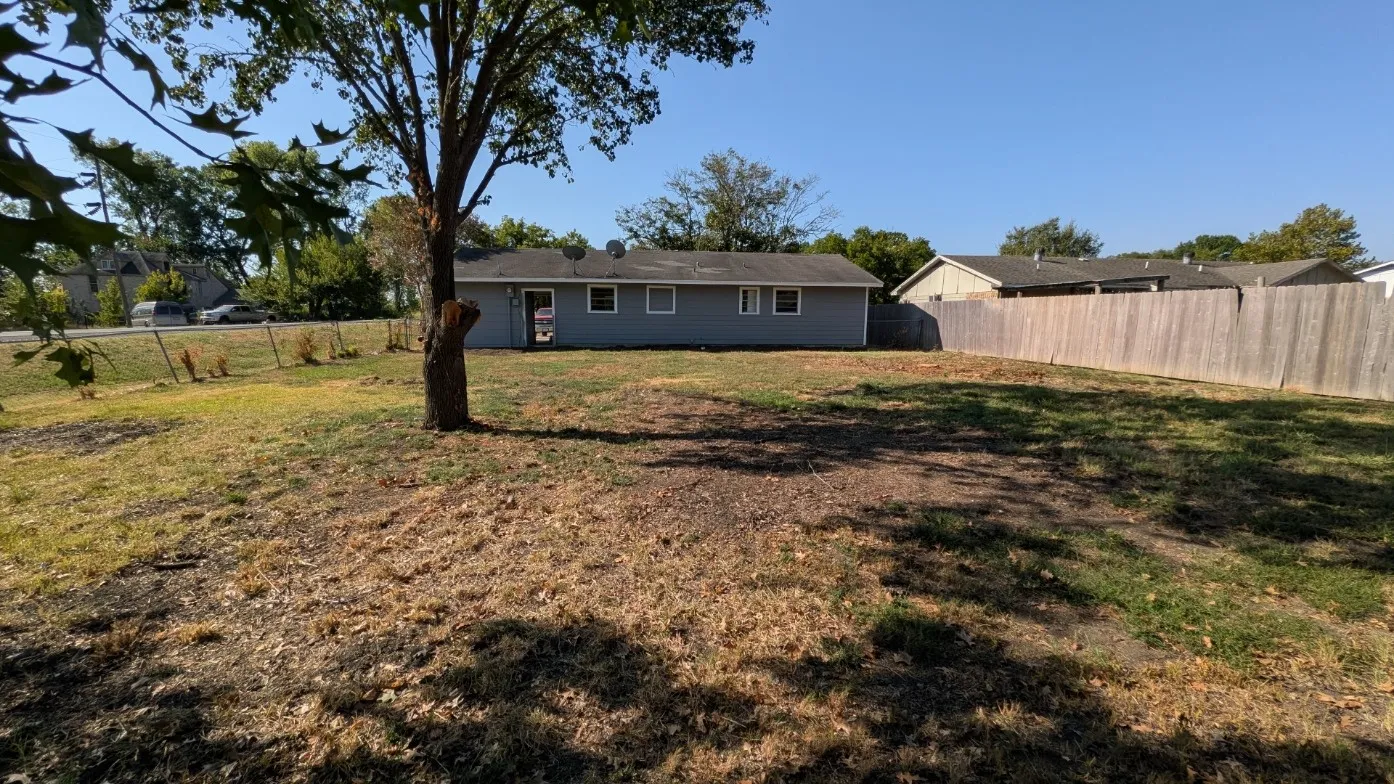 Expansive backyard featuring a mature tree and wood privacy fencing