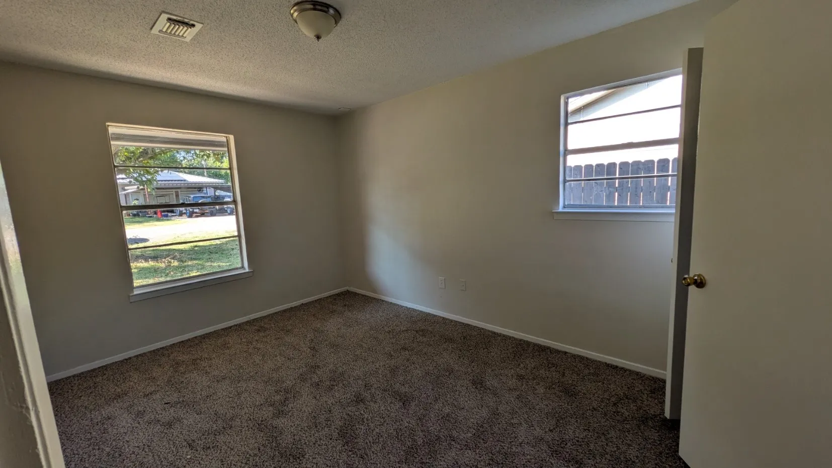 Carpeted flooring, light neutral wall paint, and two windows