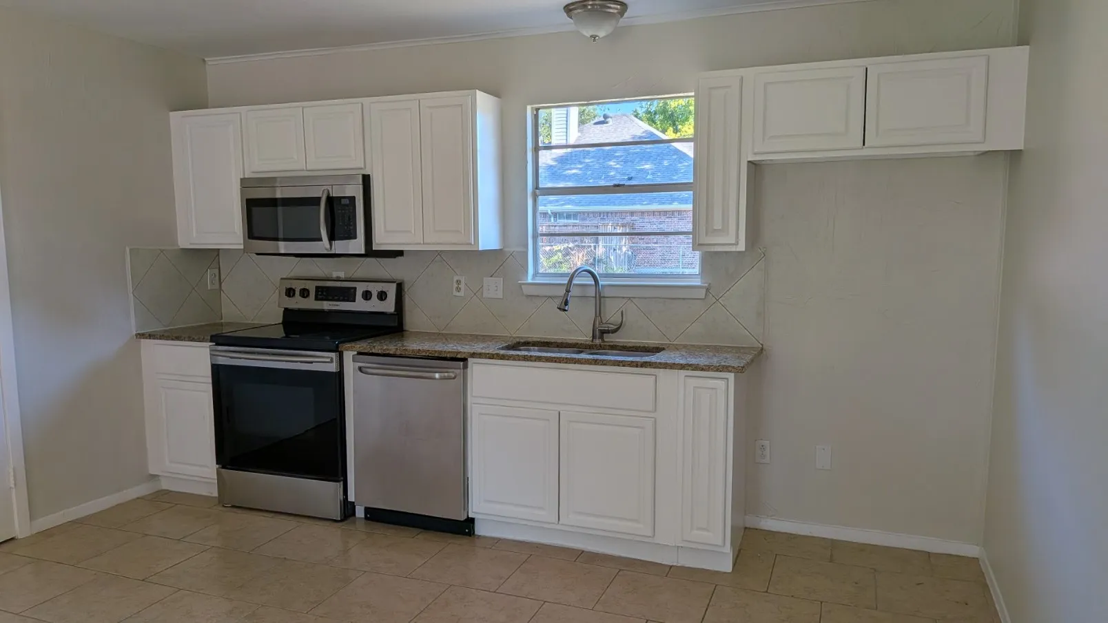 Kitchen featuring stainless steel appliances, white cabinetry, granite countertops, and tile backsplash