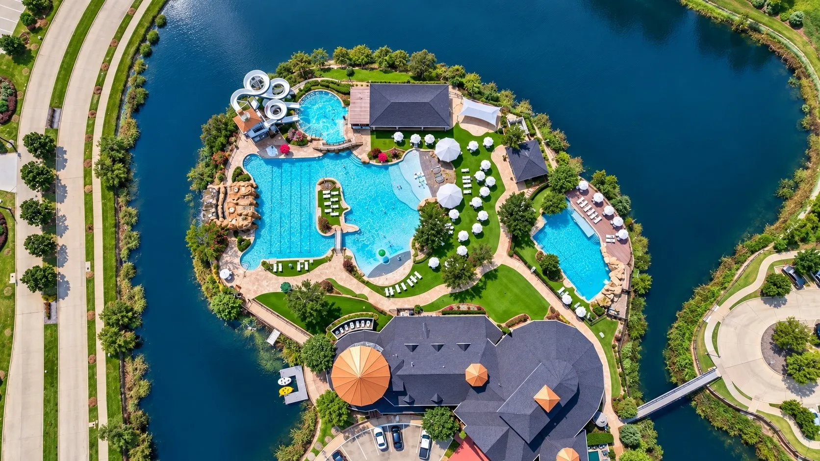 Waterfront property featuring multiple pools, water slides, extensive green spaces, and a building with a large circular roof