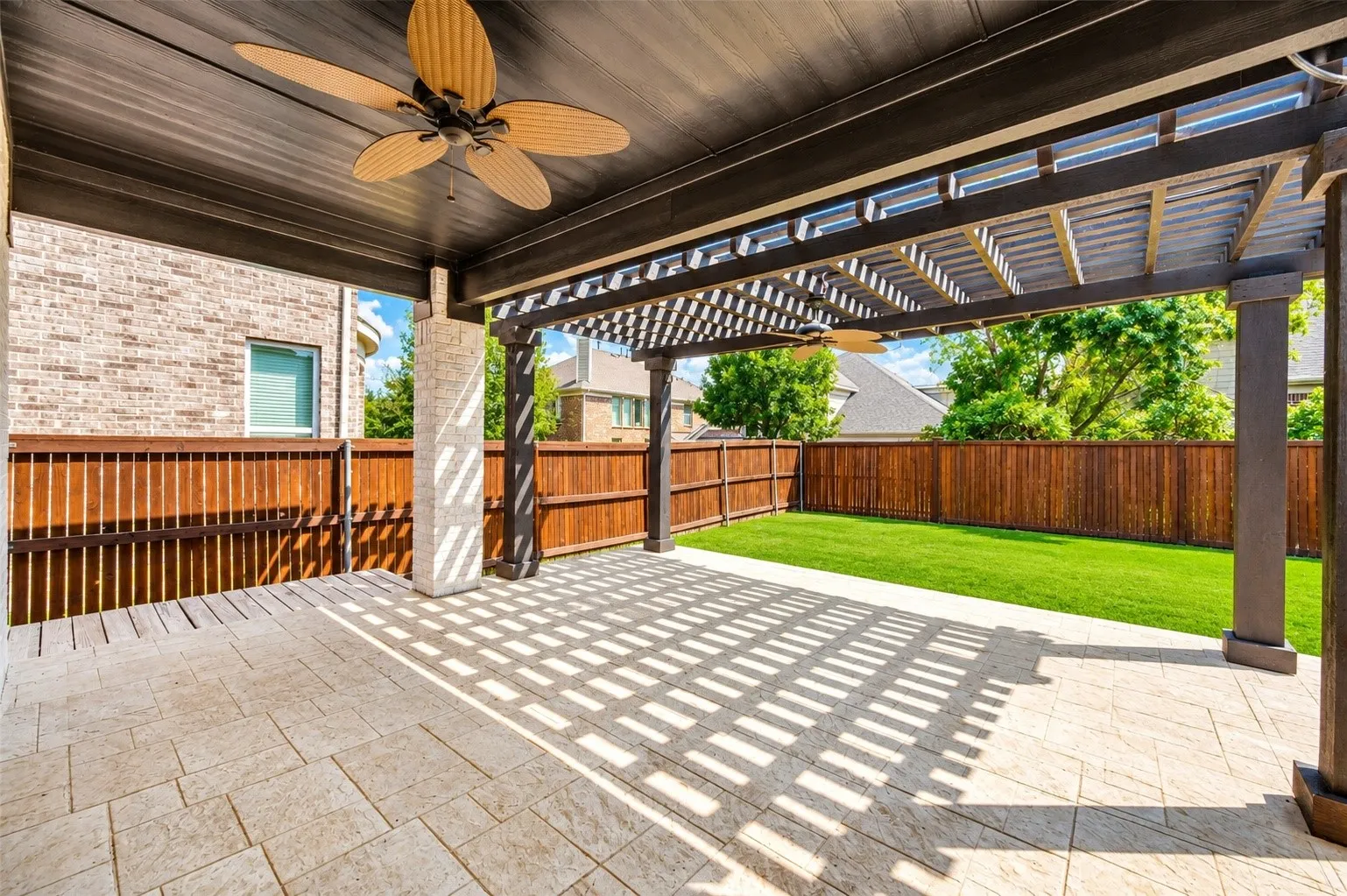 Expansive patio featuring a covered area with a ceiling fan, a pergola, and flagstone flooring