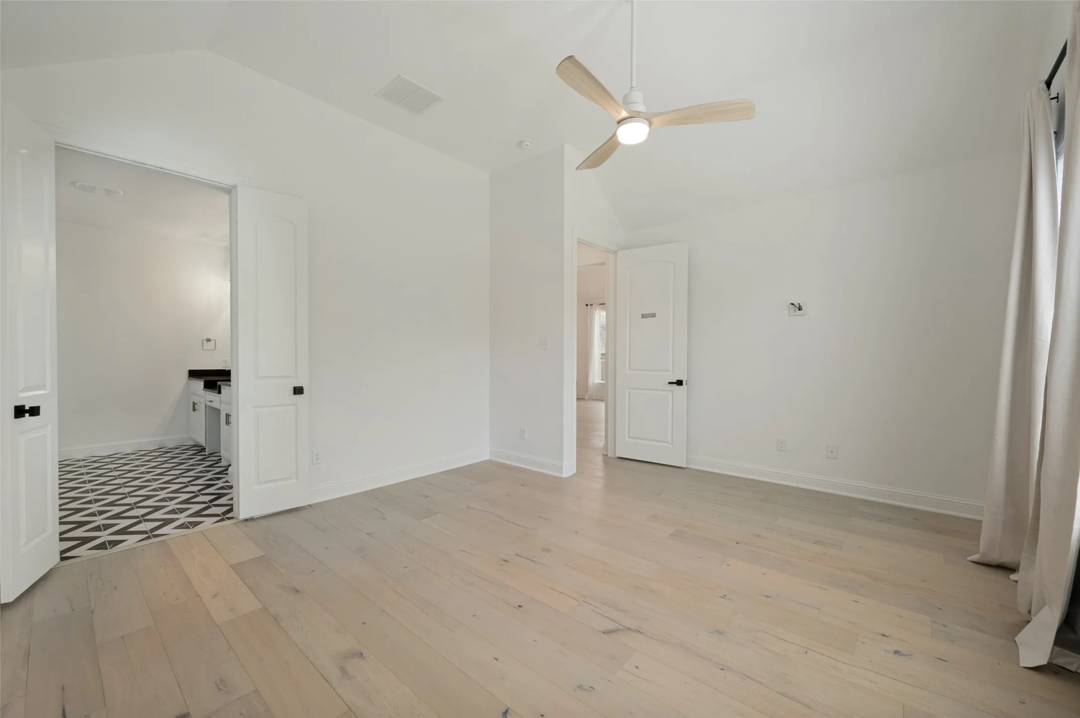 Vaulted ceiling with a contemporary ceiling fan, wide plank wood-finish flooring, and white paneled doors