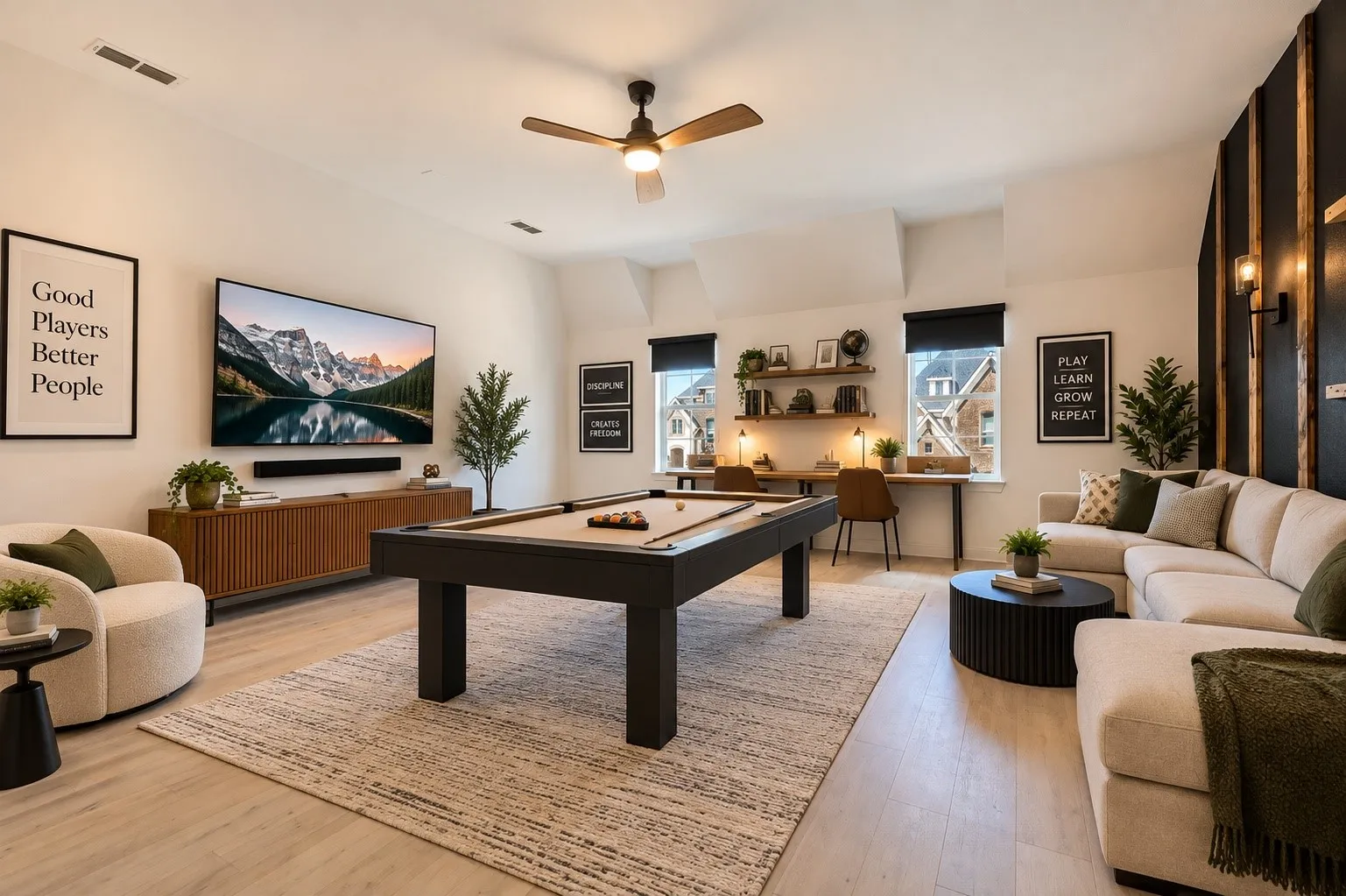 Light wood-finish flooring, built-in dual desk workspace, accent wall with wood paneling, wall-mounted television, and ceiling fan