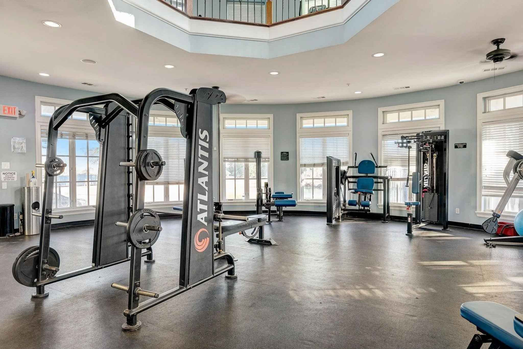 Fitness center featuring resilient flooring, multi-pane windows with blinds, and built-in exercise equipment