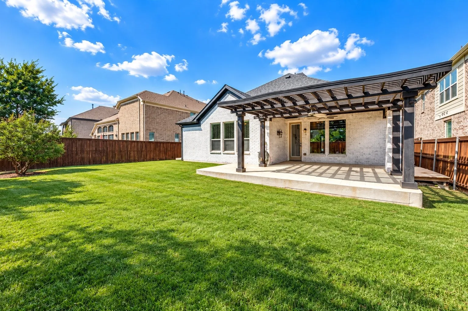 Expansive lawn, privacy fencing, dedicated patio, pergola with ceiling fan, and an additional wood deck