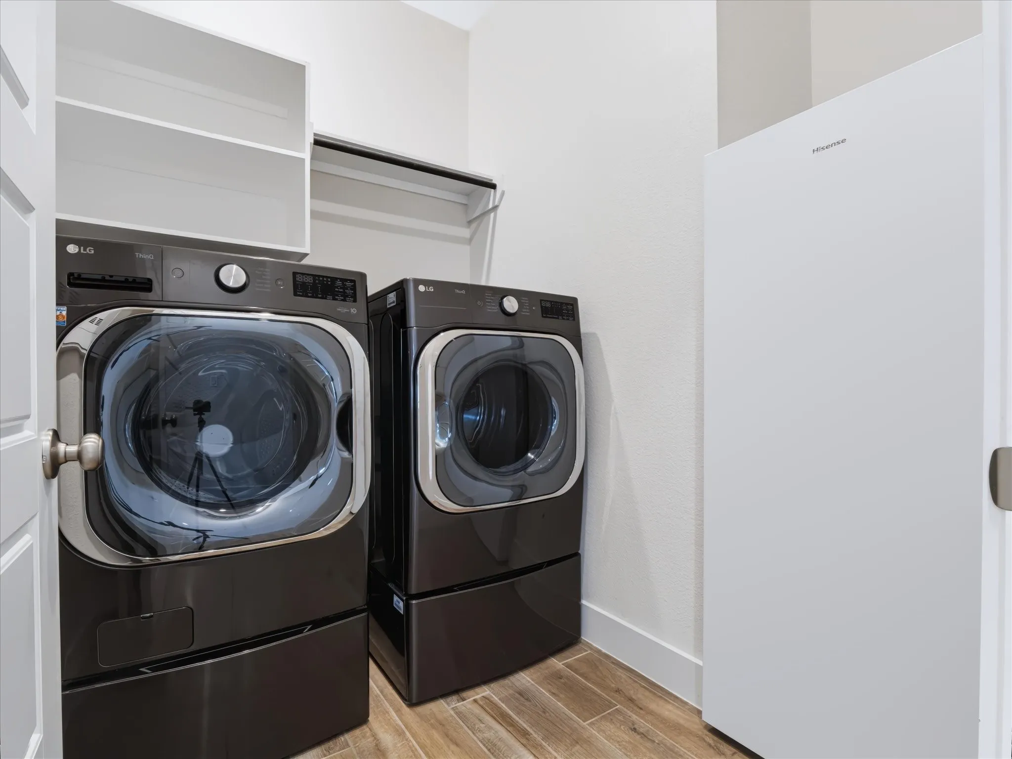 Laundry area featuring wood-finish flooring, white walls, built-in shelving, and a hanging rod