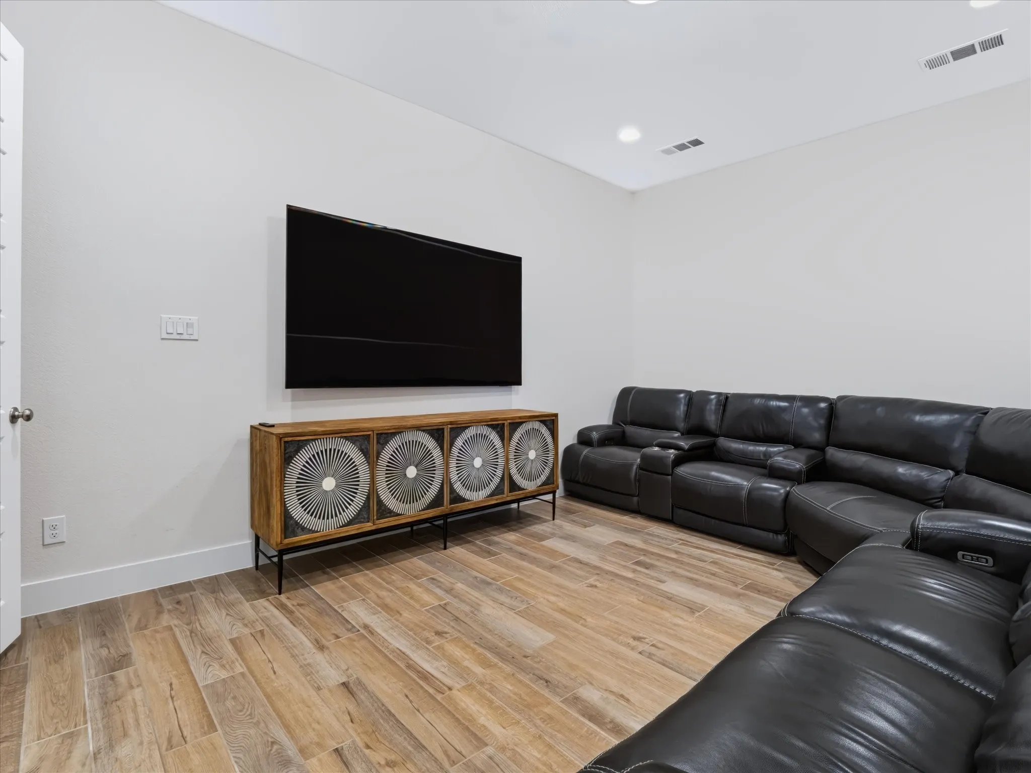 Recessed lighting, wood-finish flooring, and white walls