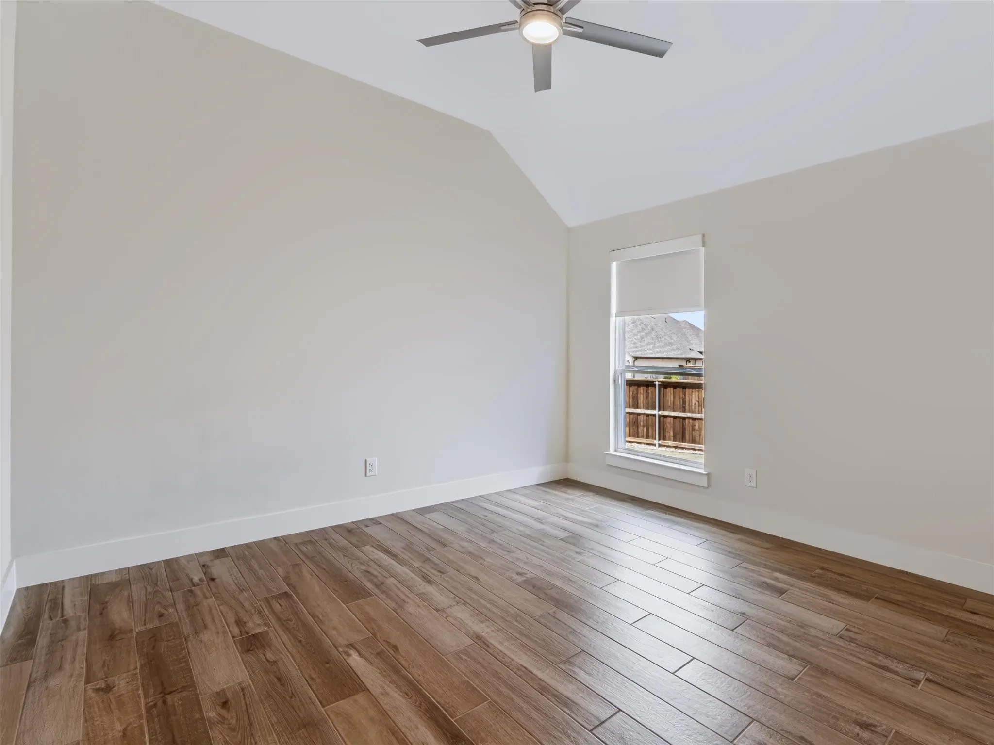 Vaulted ceiling with an attached ceiling fan, wood-finish flooring, and white trim molding