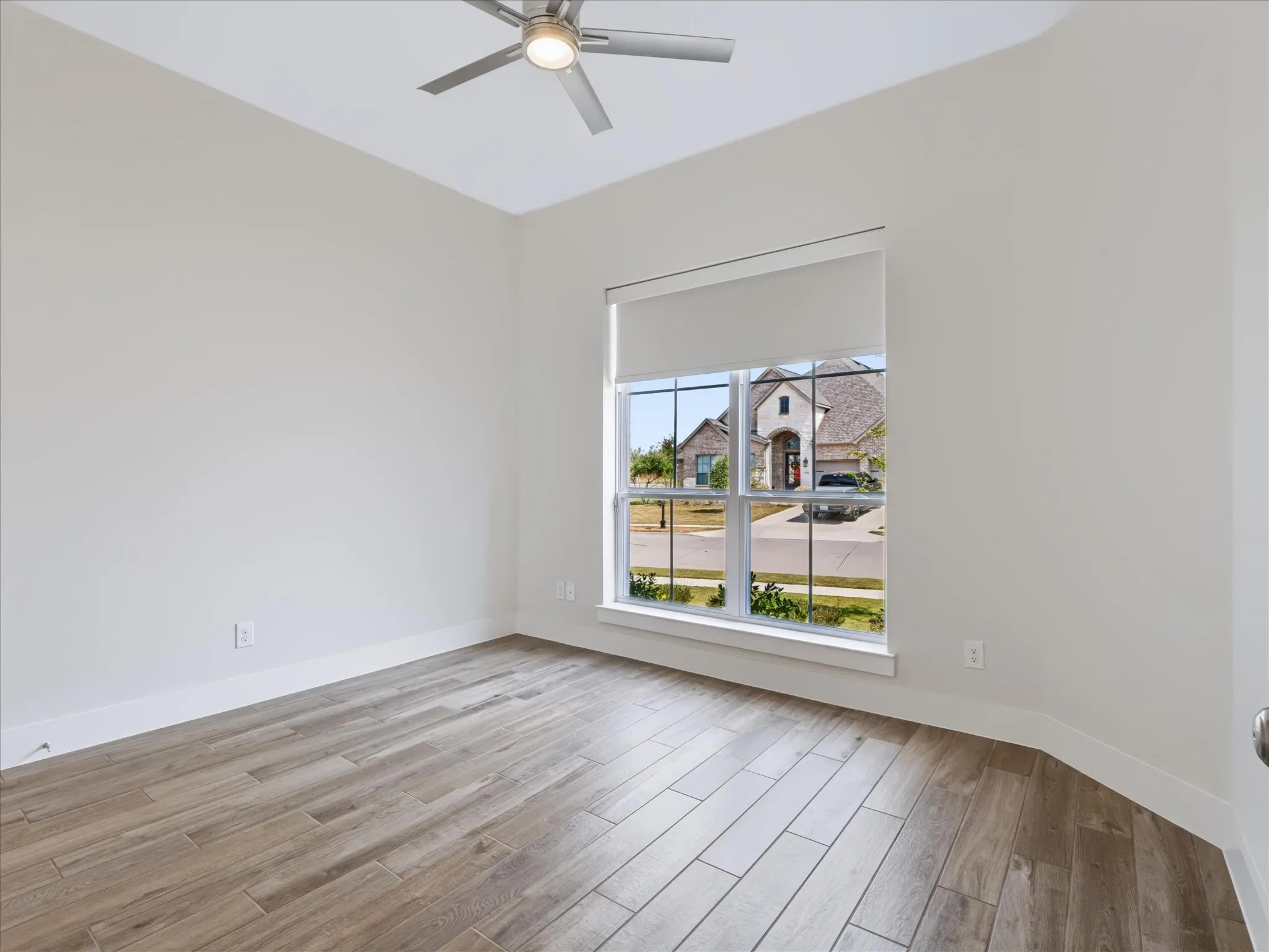 Wood-finish flooring with a modern ceiling fan and large window