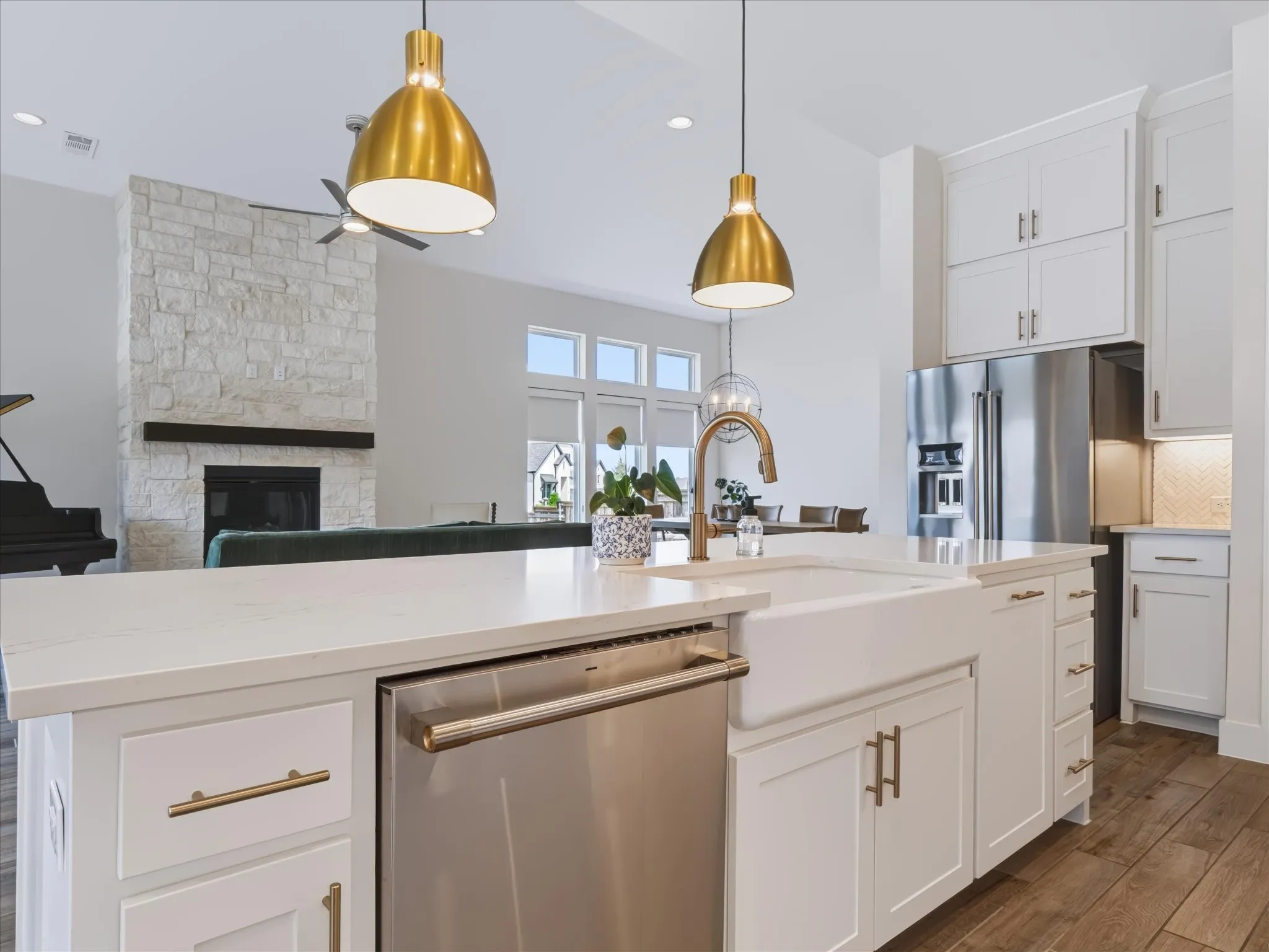 Kitchen island featuring a farmhouse sink, stainless steel dishwasher, and brass-finish hardware