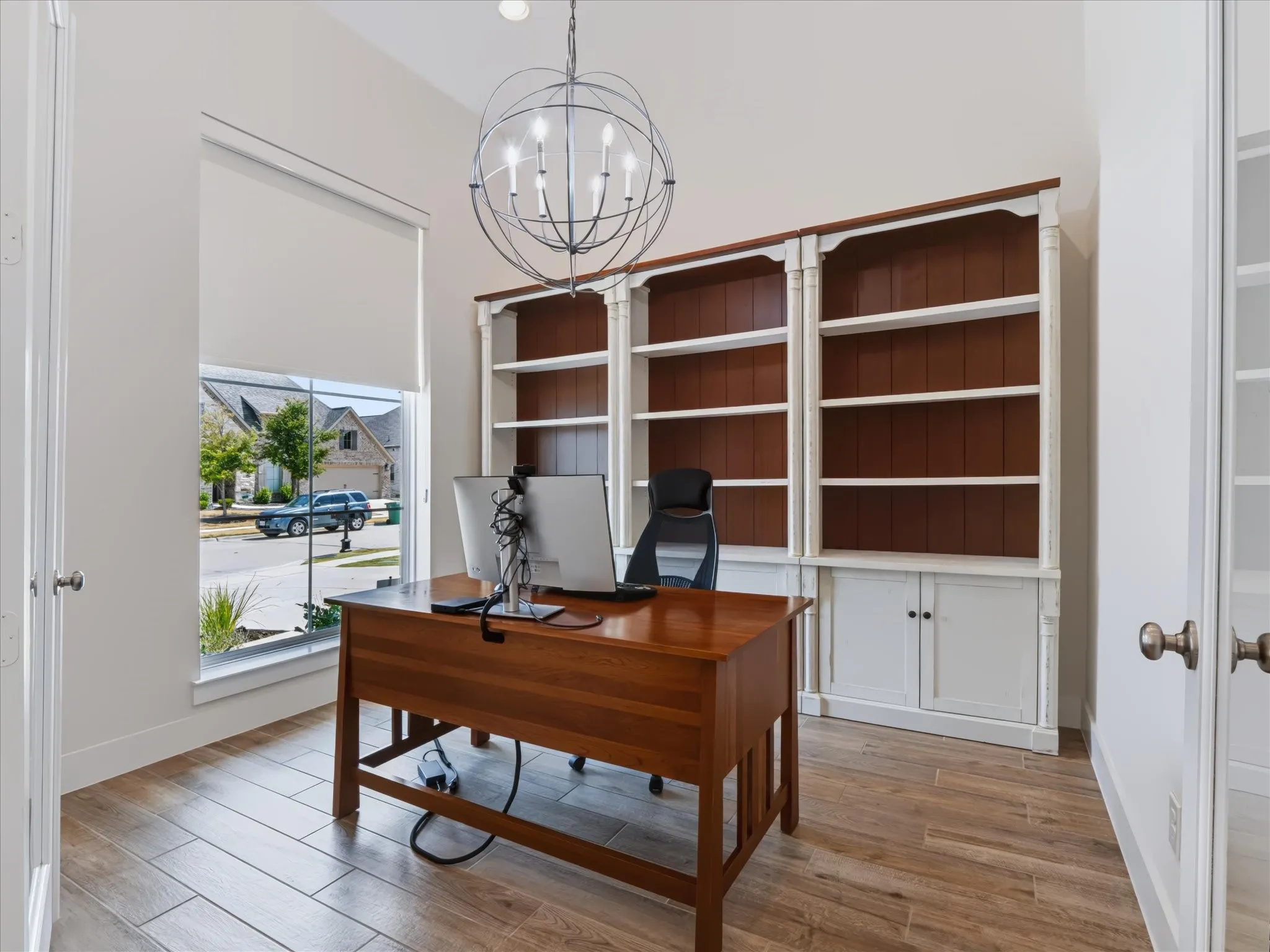 Vaulted ceiling with an orb chandelier, wood-finish flooring, and built-in white cabinetry with dark wood backing