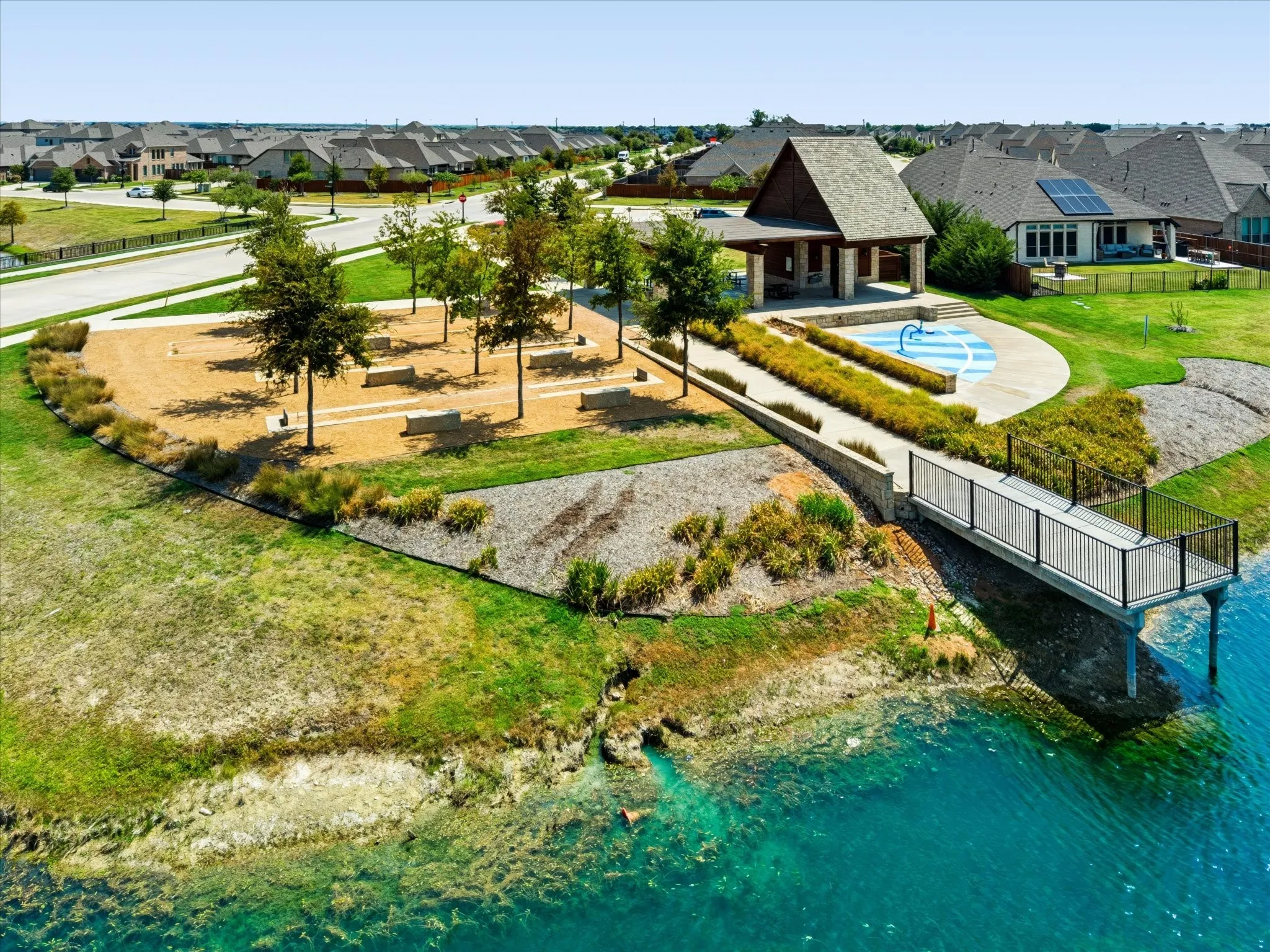 Waterfront property featuring a dock, a covered outdoor pavilion, a water play area, and a landscaped park with trees