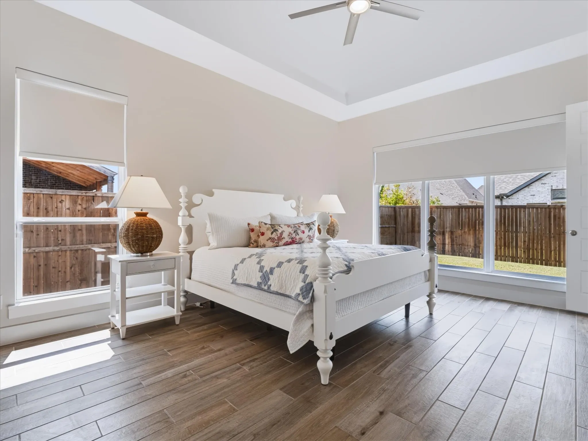 Tray ceiling with recessed lighting, ceiling fan, wood-finish flooring, multiple windows, and a white paneled door