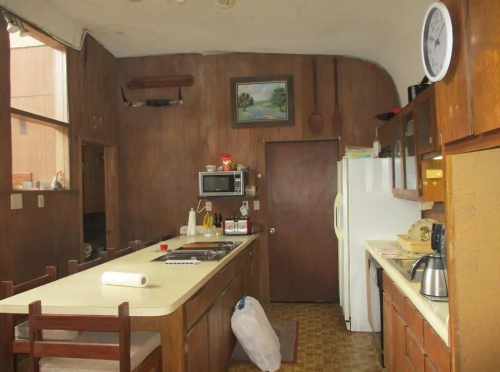 Kitchen featuring wood-panel walls, a built-in cooktop, and a peninsula with seating