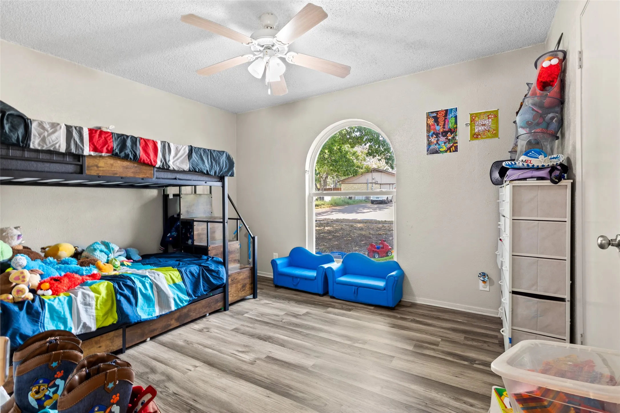 Arch-top window, wood-finish flooring, ceiling fan, and light-toned walls