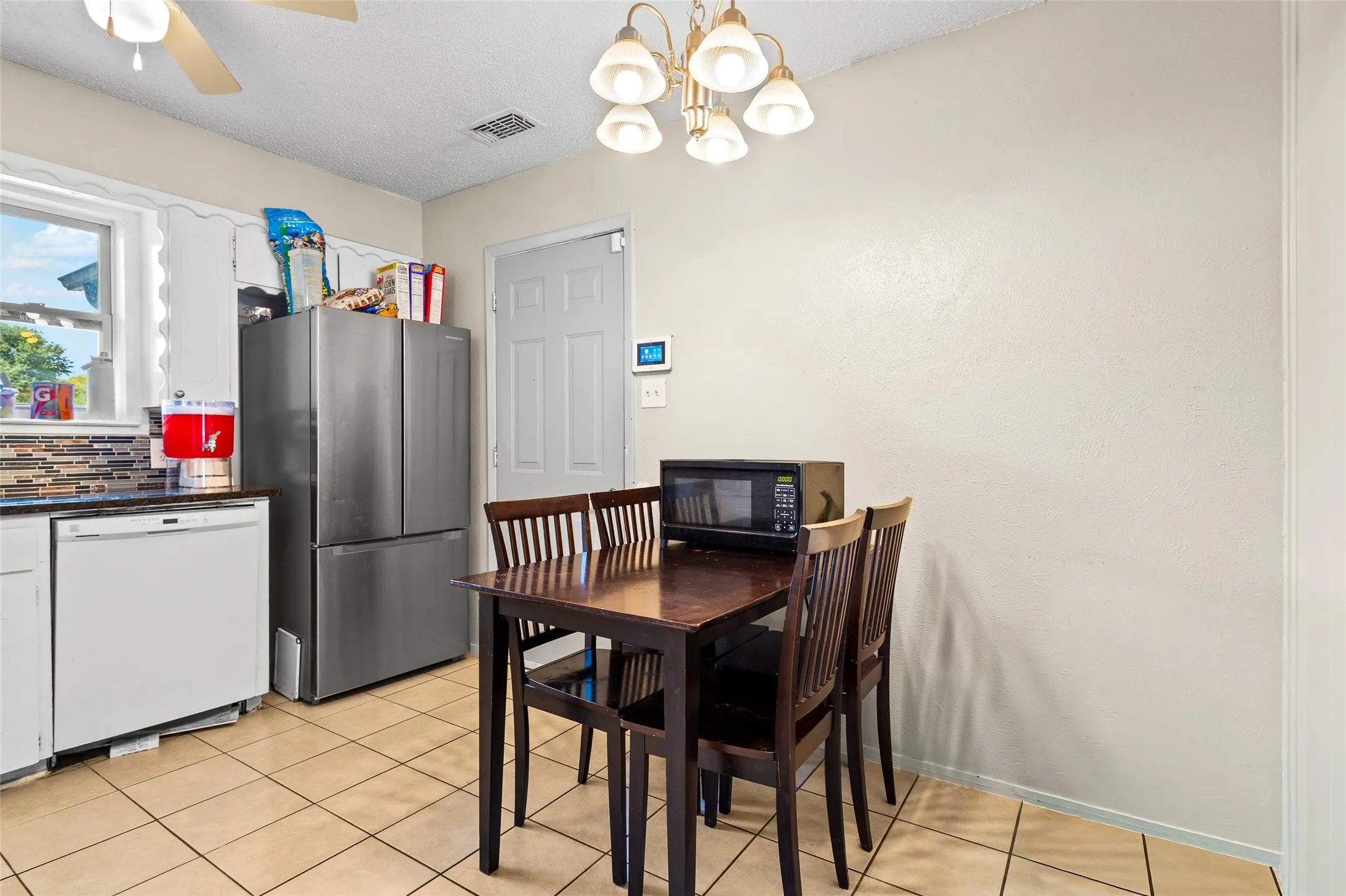 Kitchen featuring tile flooring, a window, a ceiling fan, and a built-in dishwasher