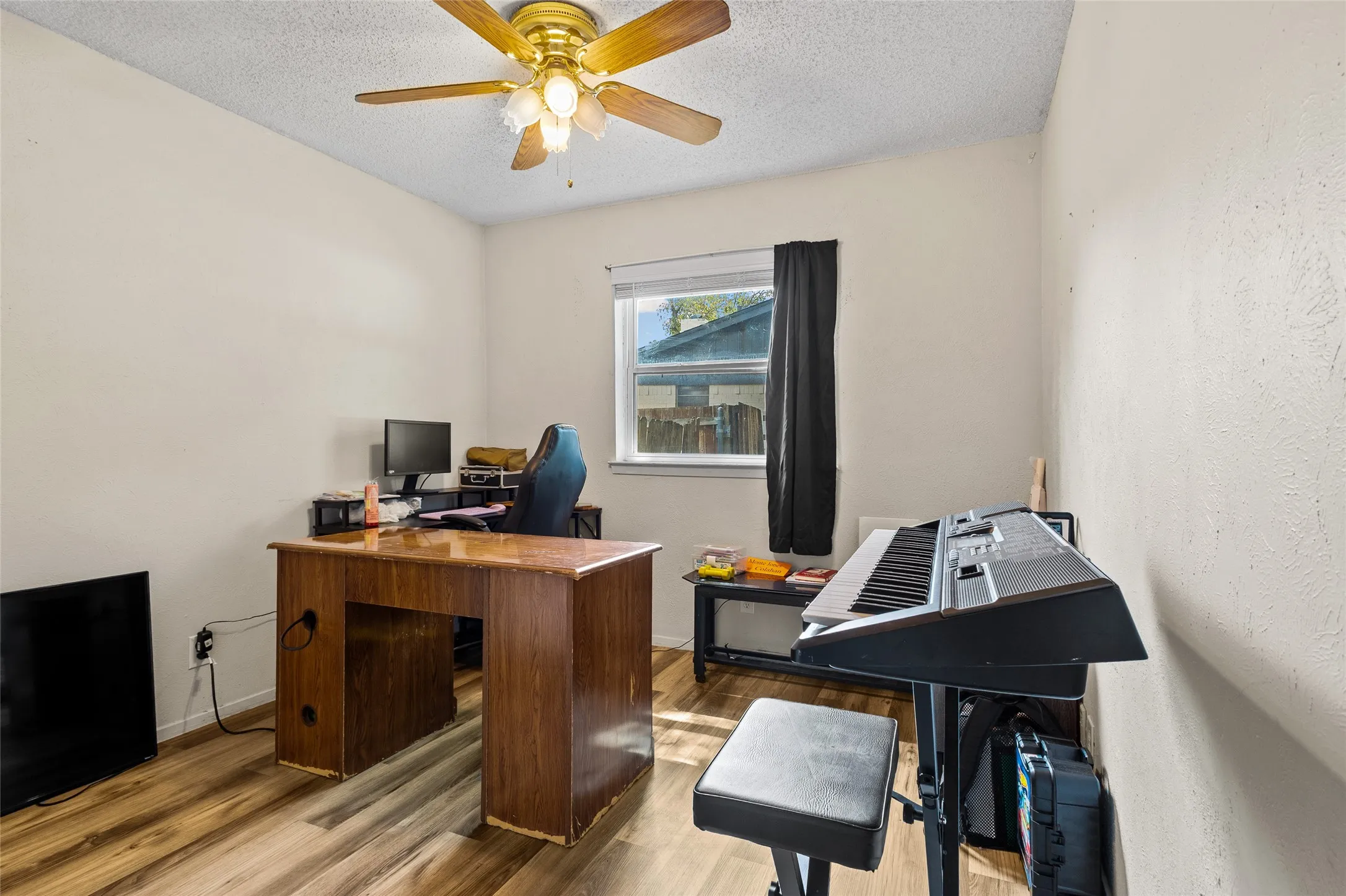 Wood-finish flooring, ceiling fan with integrated lighting, and a window with natural light