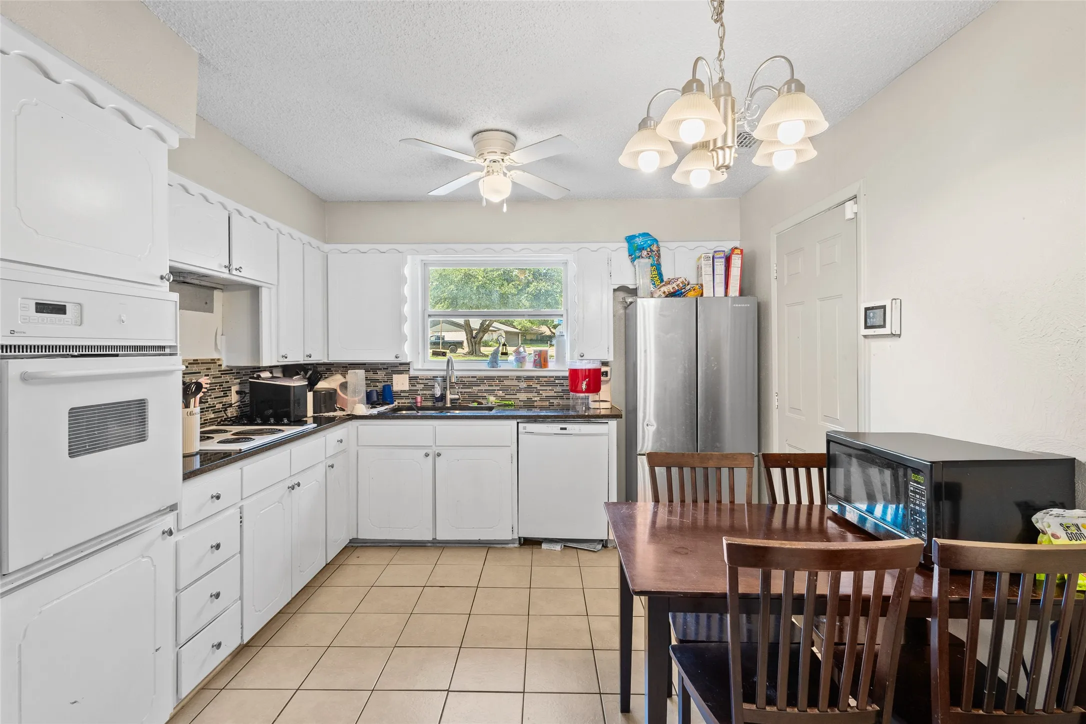 Kitchen featuring white cabinetry, black countertops, tiled flooring, and a built-in oven