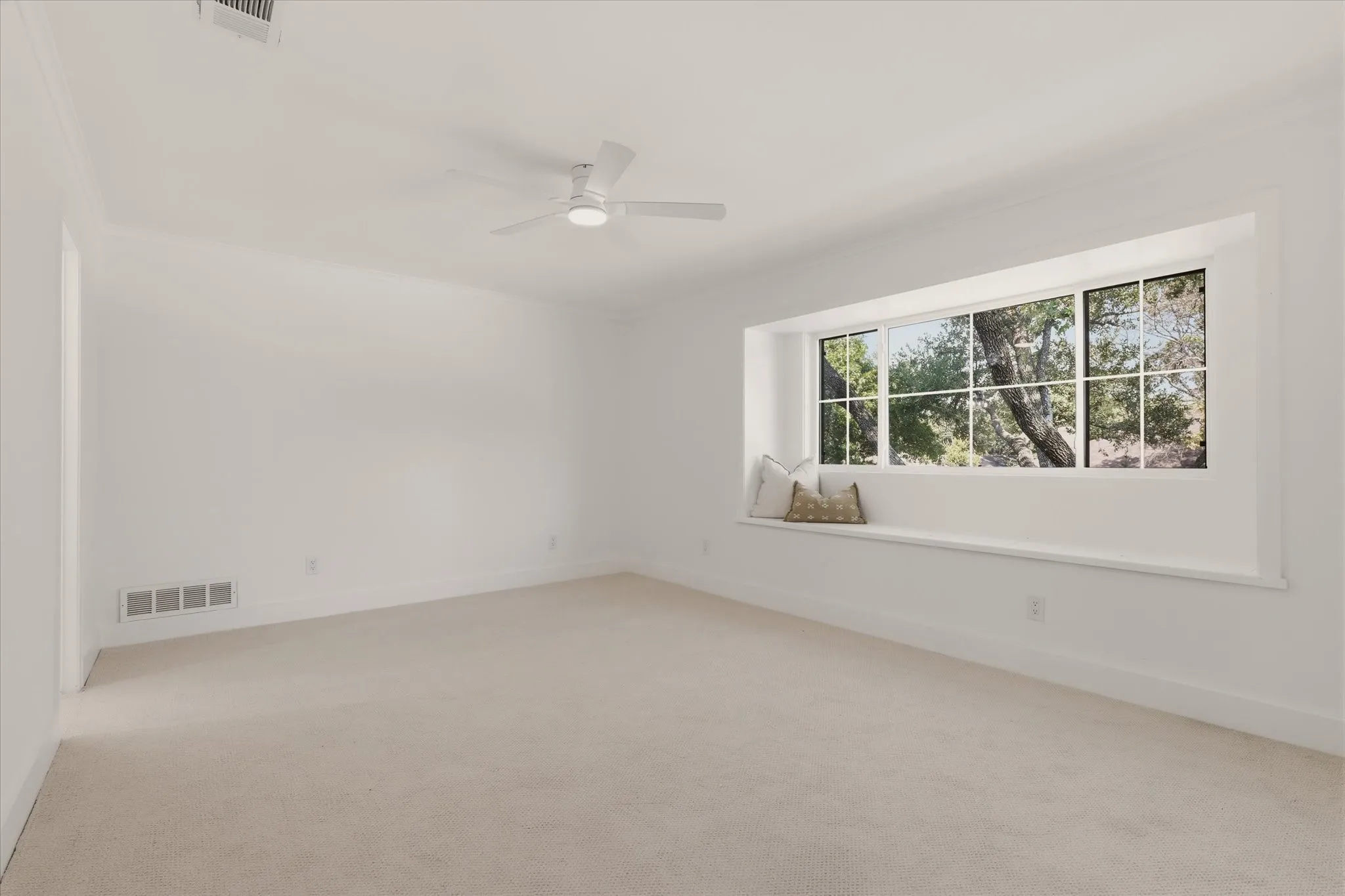 Expansive room with neutral carpet, large picture window, and a built-in window seat