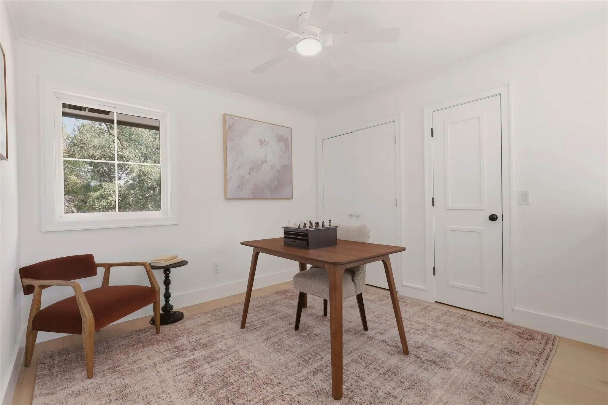 Light wood-finish flooring, white walls, and a ceiling fan with integrated lighting